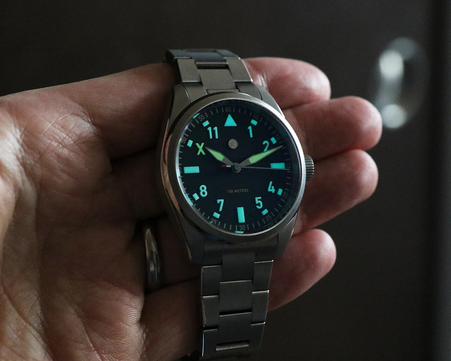 a man holds a jack mason pilots watch with glowing indices