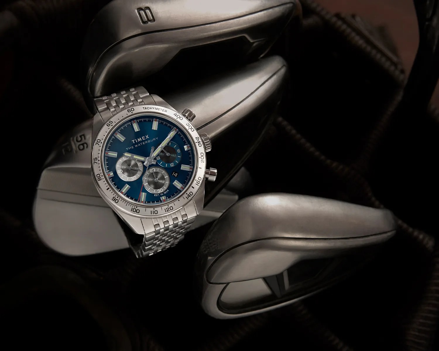 a timex chronograph watch on some golf clubs