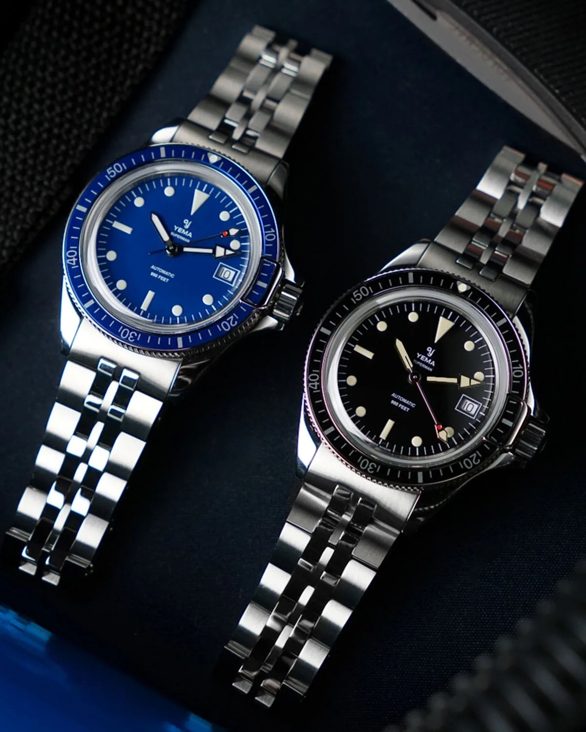 a black dive watch and blue dive watch laying next to each other