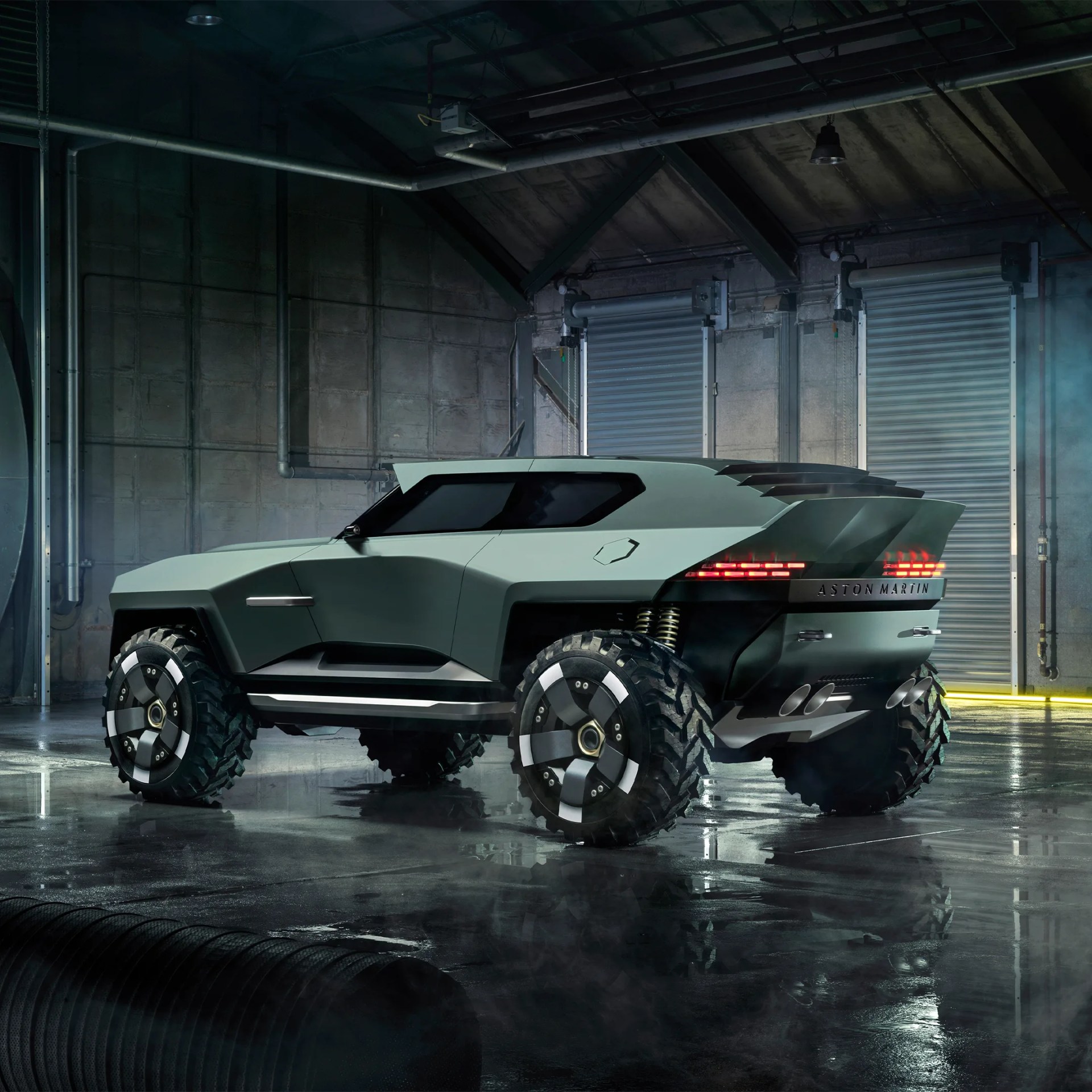 Matte green Aston Martin SUV with large off-road tires in a dimly lit industrial garage.