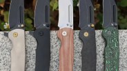 Closeup of Kansept Superhawk knives on slate in front of flowers
