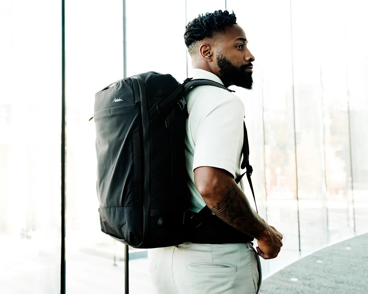 Man wearing Matador GlobeRider35 Travel Backpack in front of windows