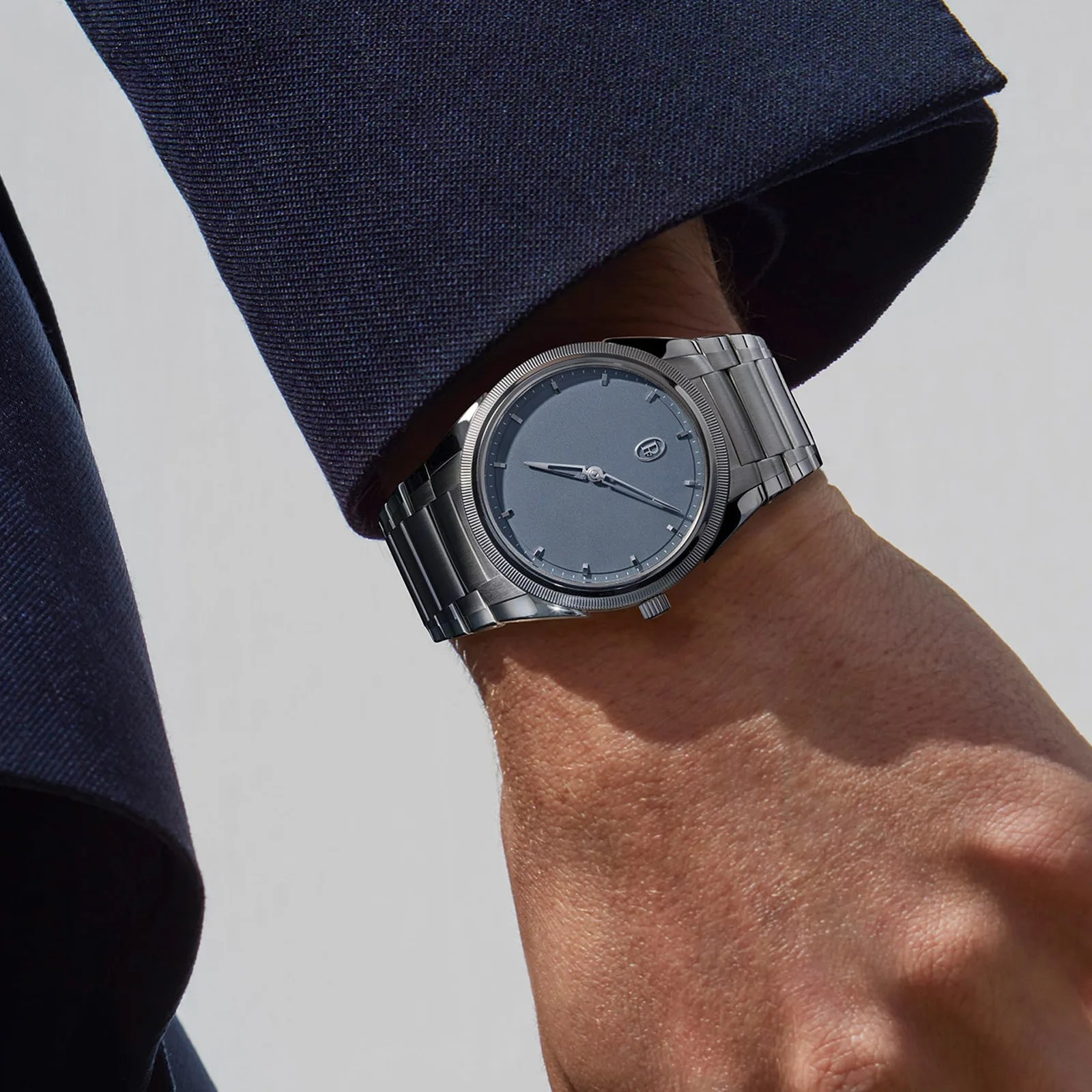 The Parmigiani PF Micro-Rotor Platinum Stone Blue worn on wrist of a mail wearing a navy blazer.