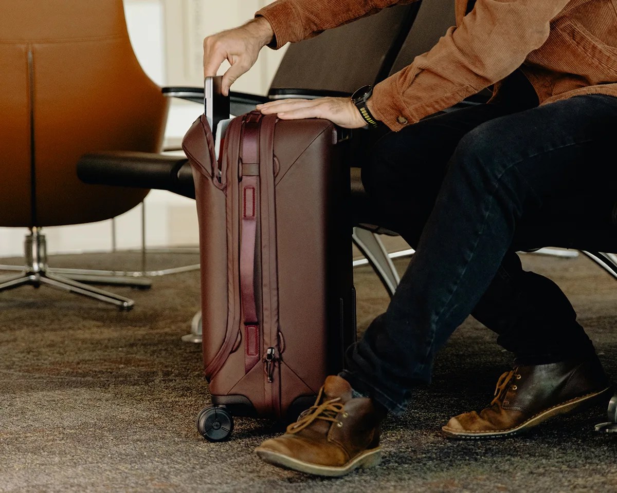 Peak Design Roller Pro Carry On bag in airport with man extracting laptop
