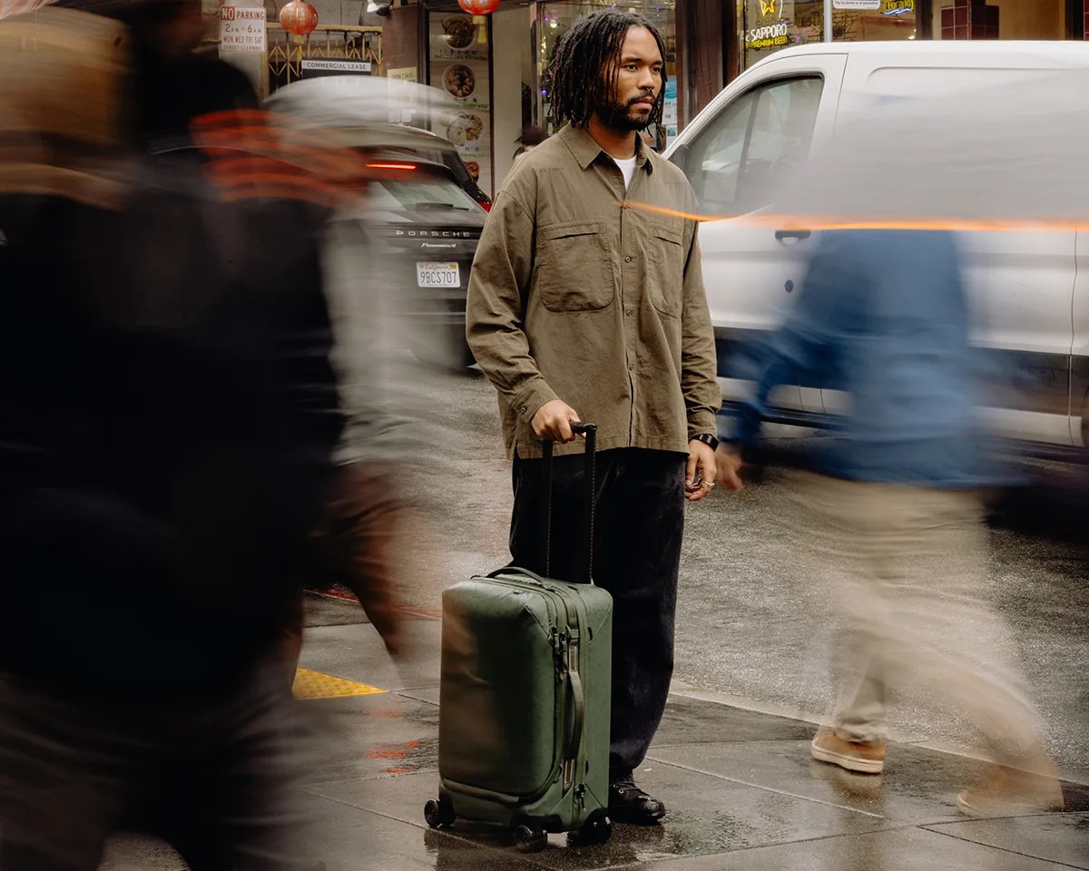 Man holding handle of Peak Design Roller Pro Carry On on city street