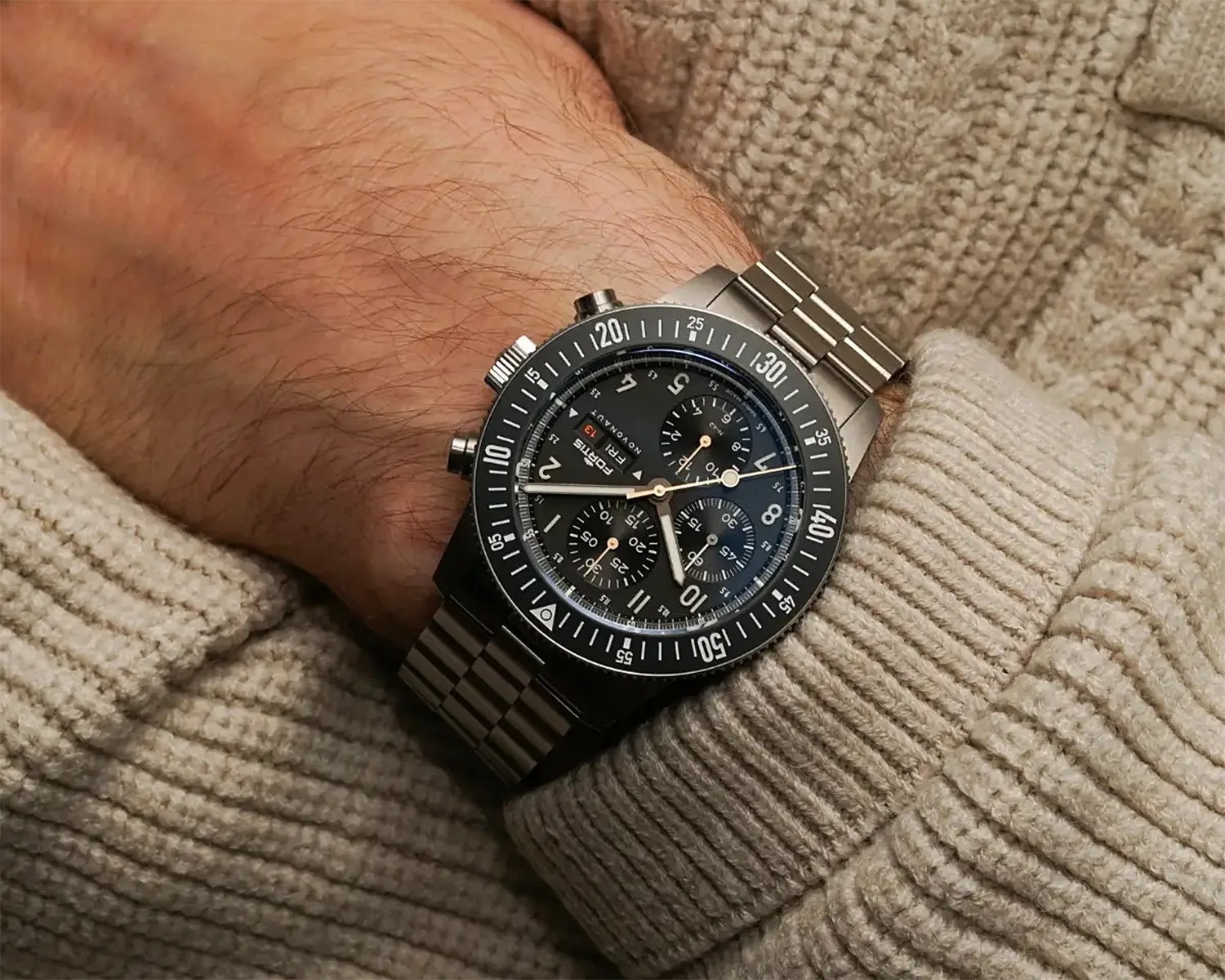 a black dial chronograph watch on a man's wrist