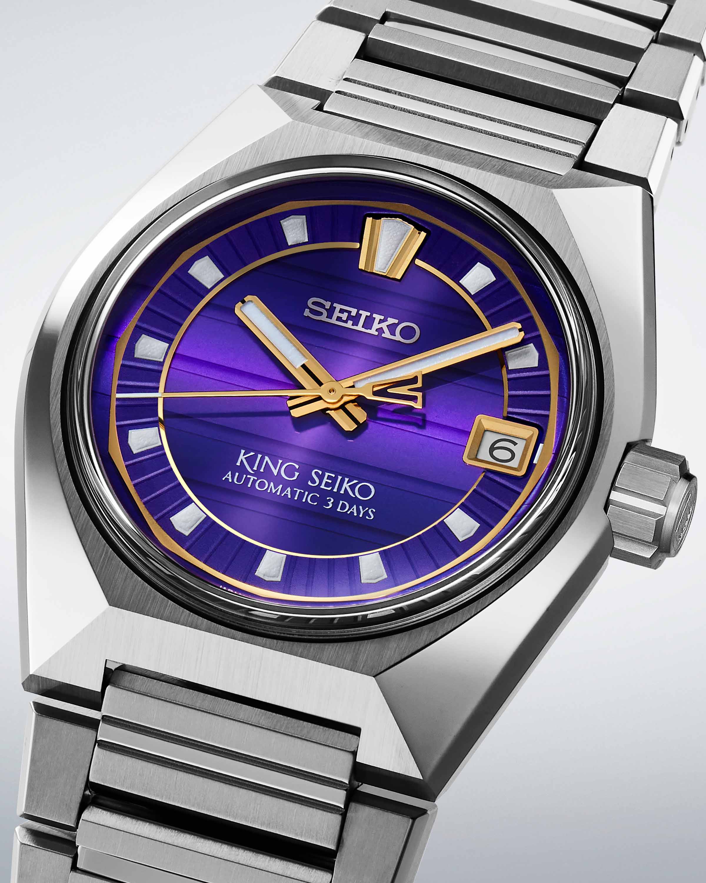 a steel Seiko watch with a purple and gold dial
