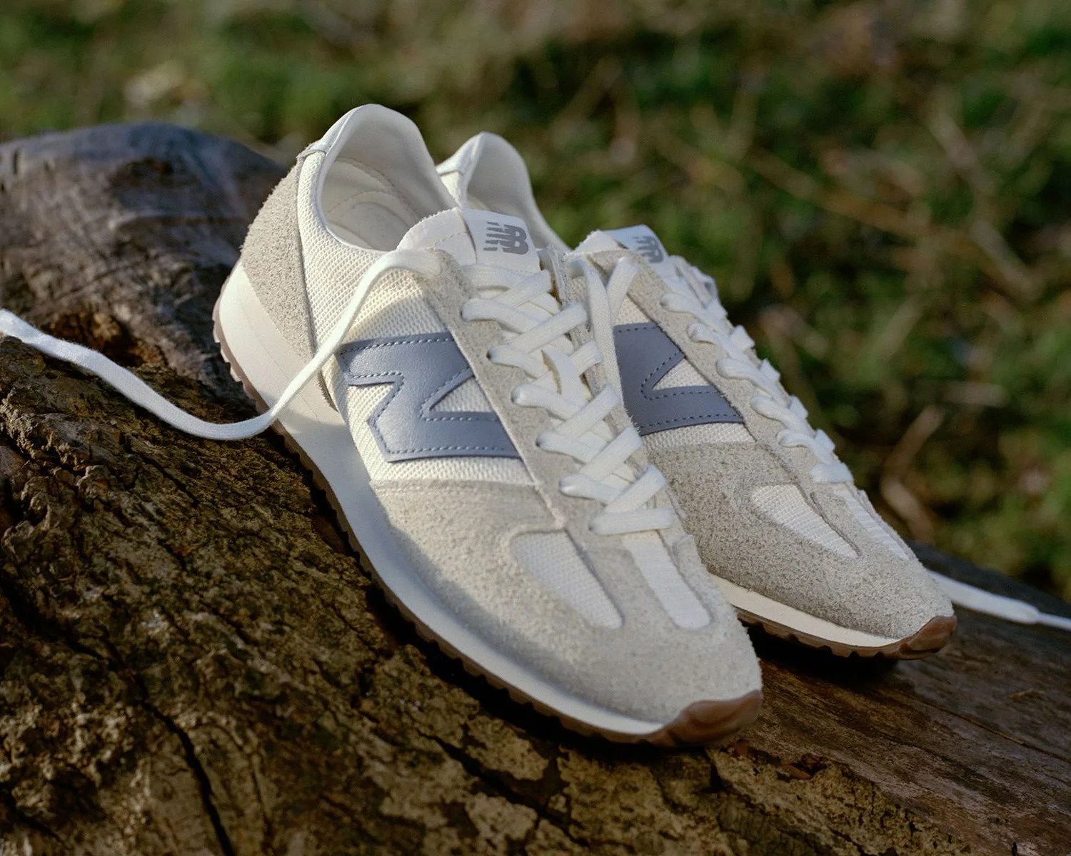 a pair of white New Balance sneakers on a log