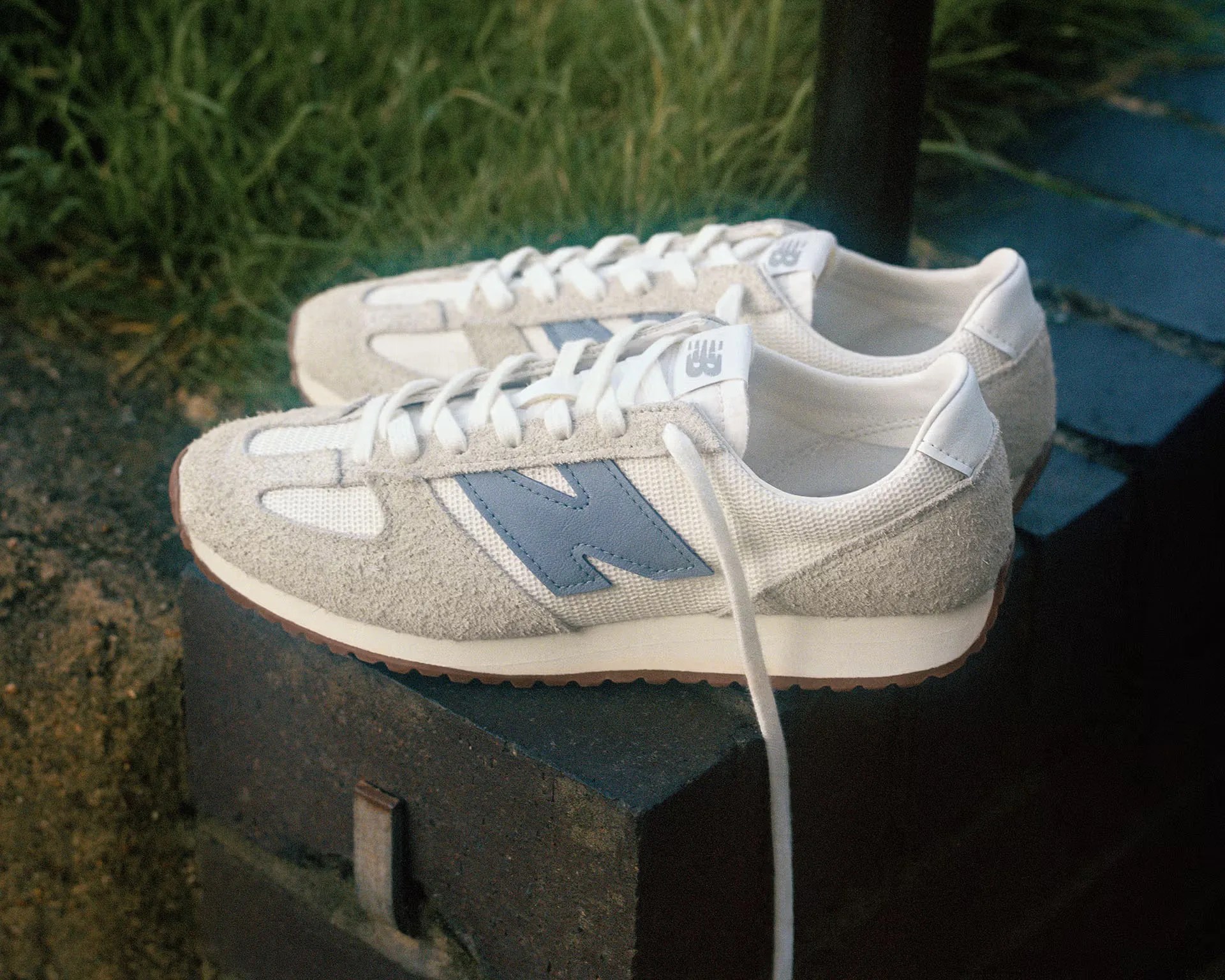 a pair of white New Balance running shoes on a brick wall