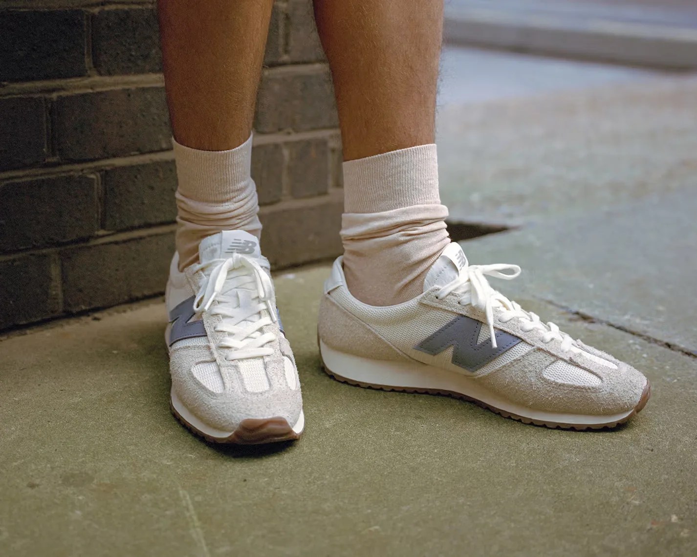 a pair of white New Balance running shoes on someones feet