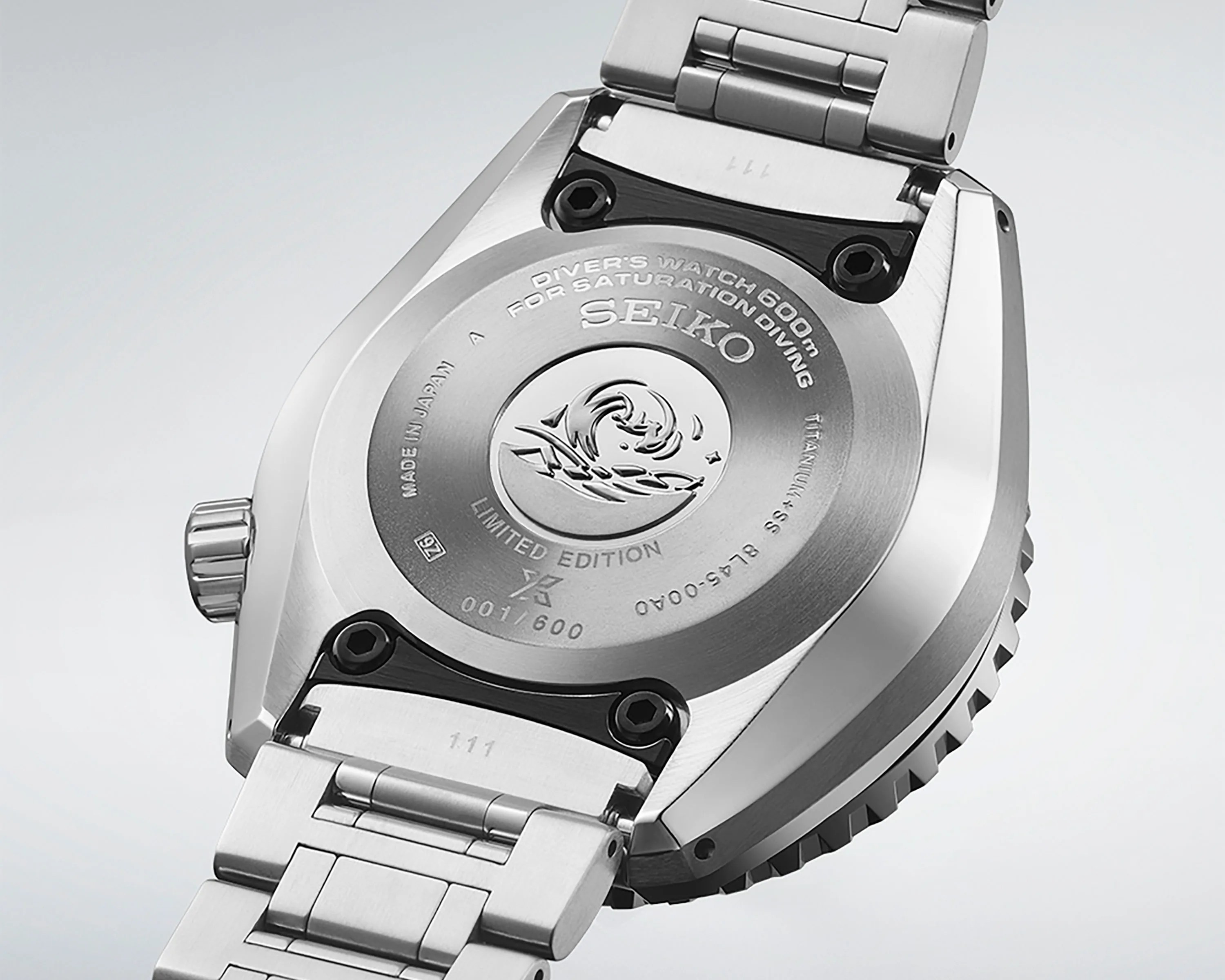 the steel case back of a Seiko watch with the brand's wave log engraved on it