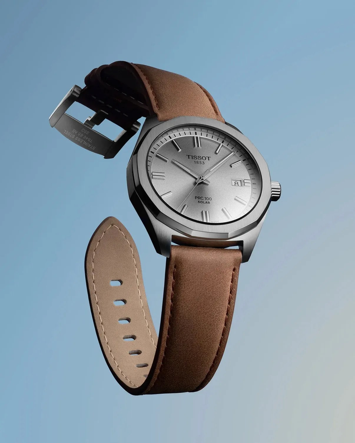 a silver dial steel watch with a brown leather strap