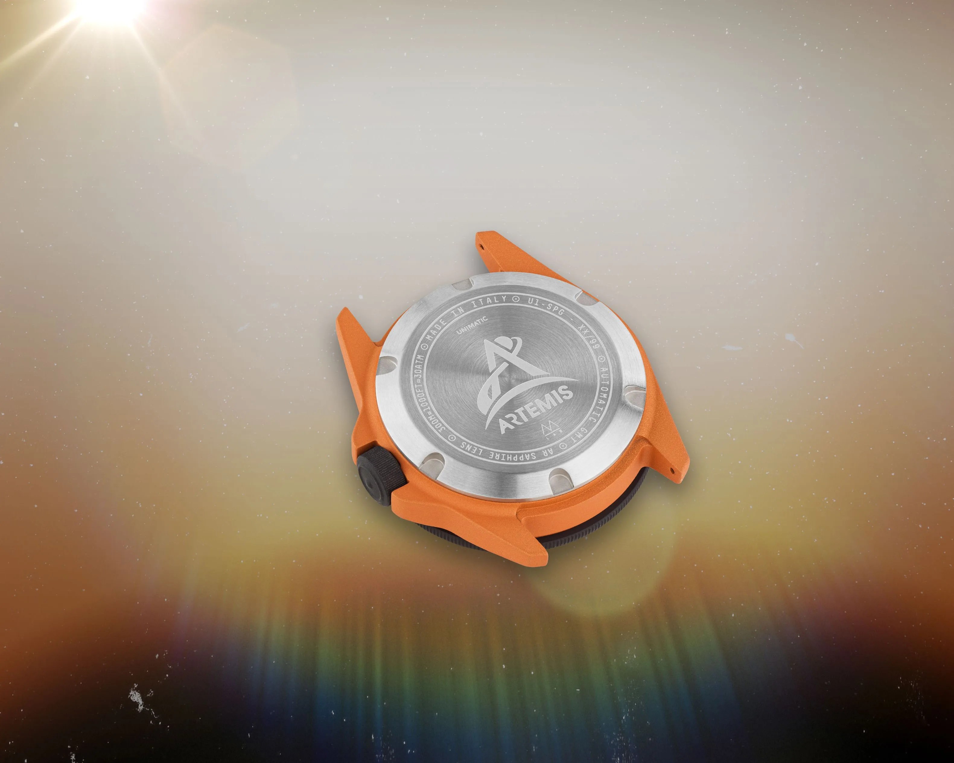 an orange watch with a steel case back engraved with the Artemis space program logo