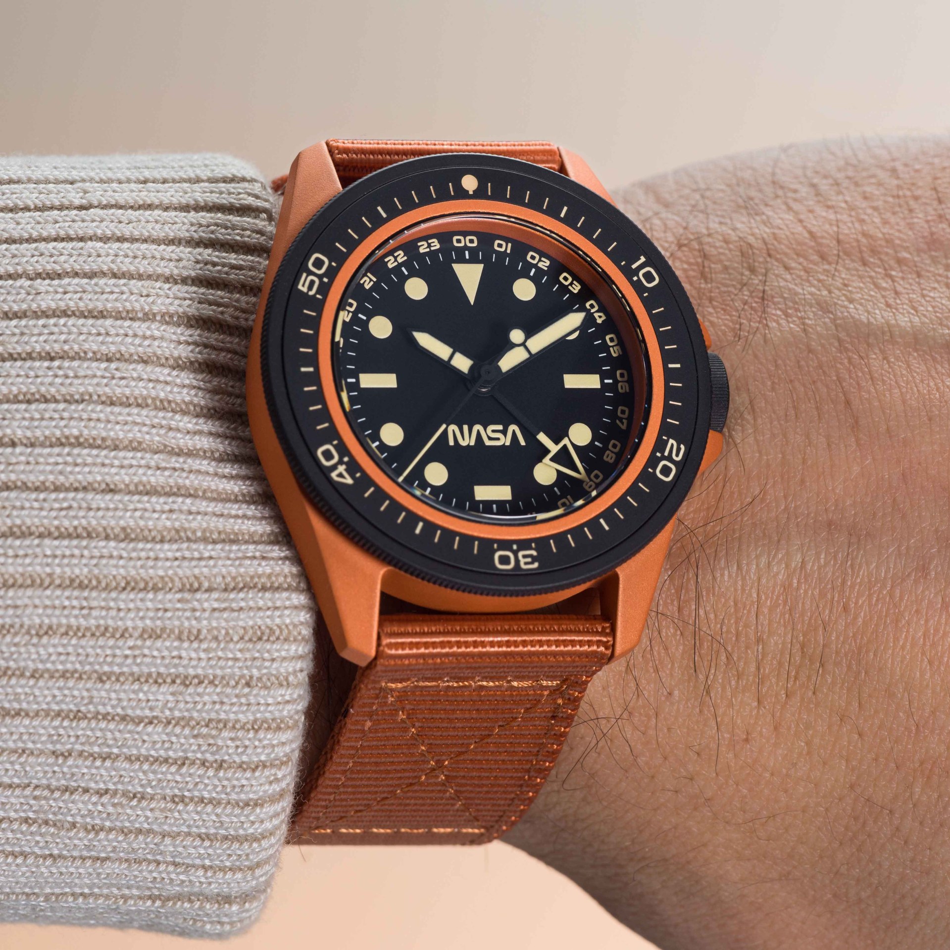 an orange watch with a black dial and bezel on a man's wrist