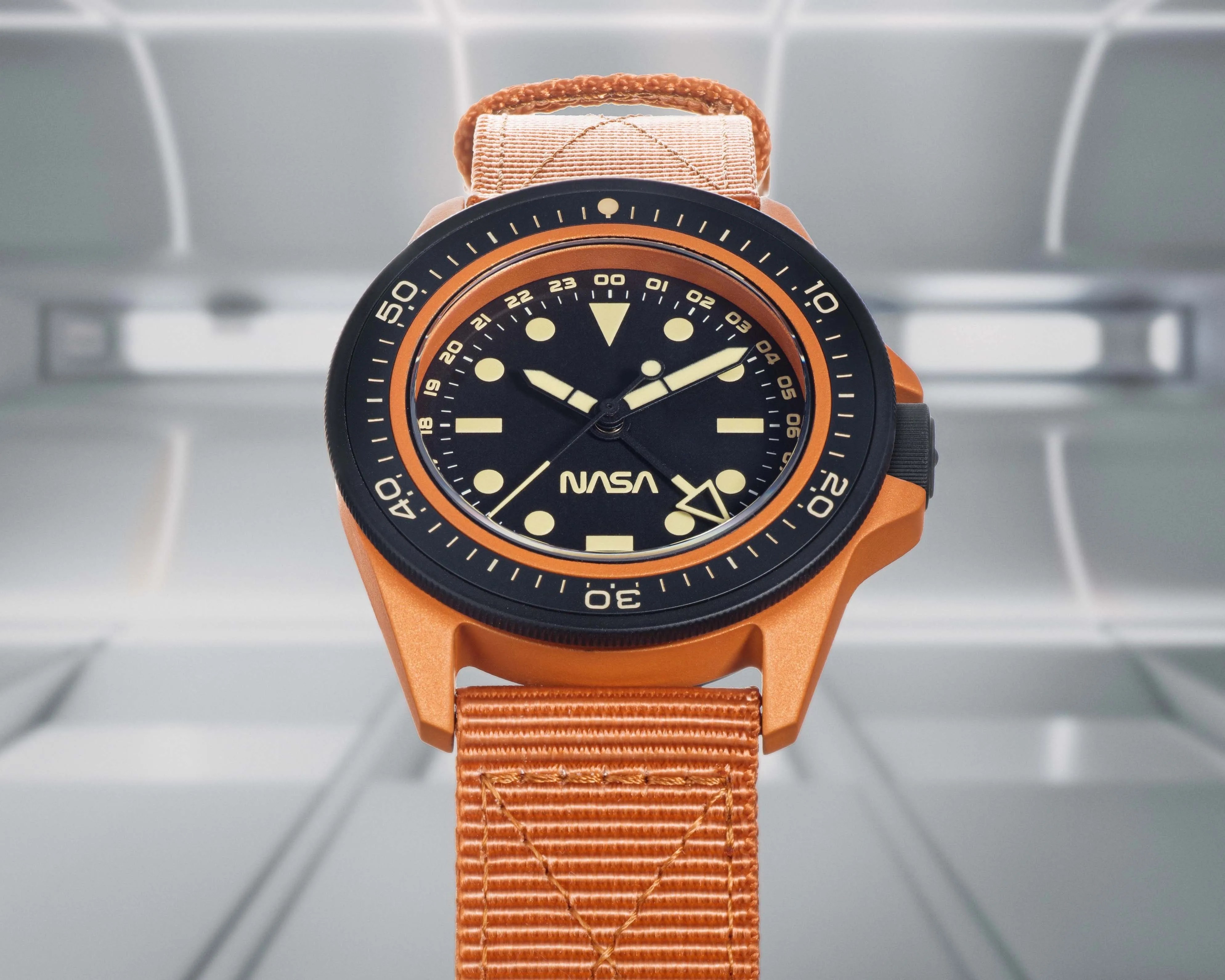 an orange watch with a black dial that says NASA