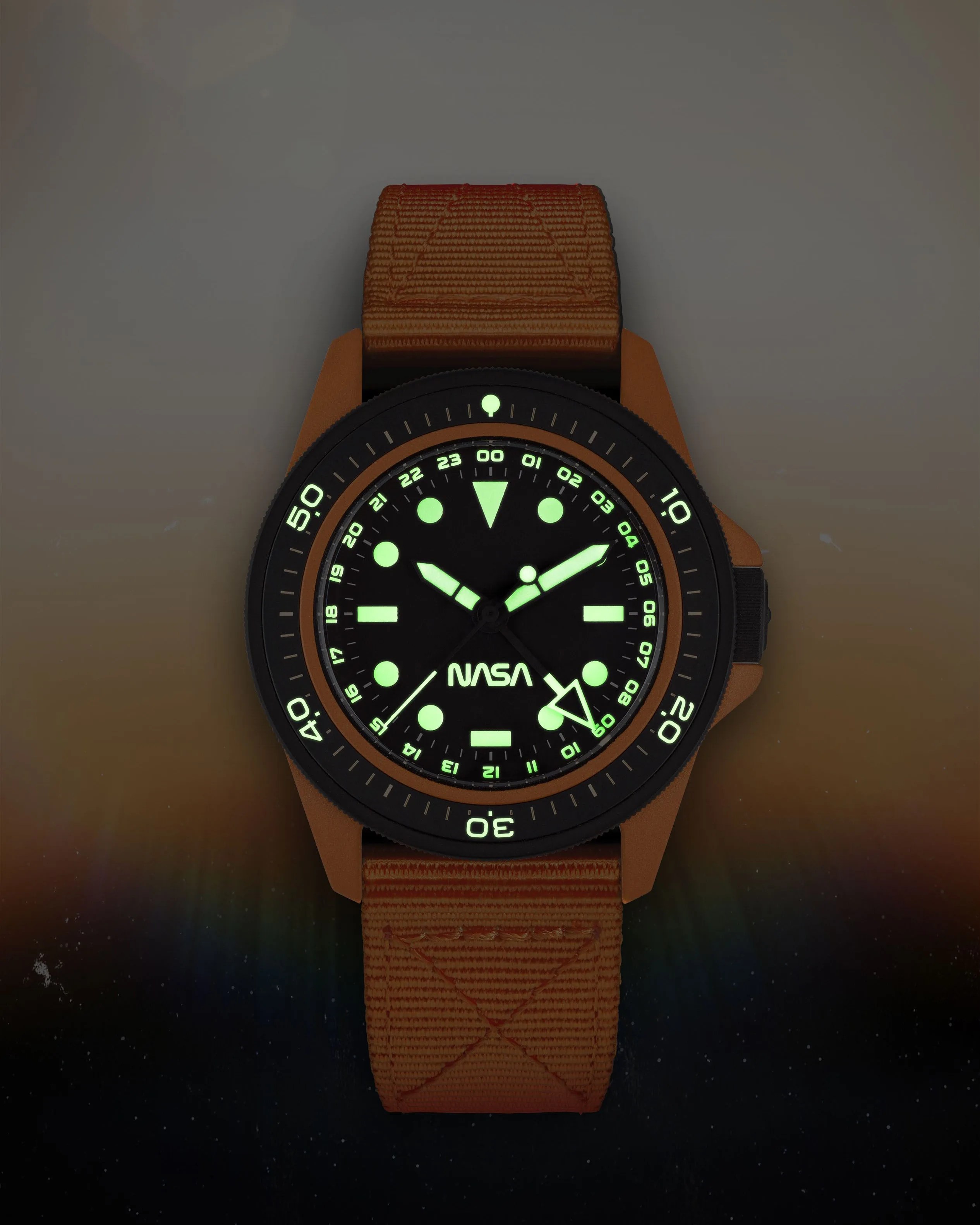 an orange and black watch with the dial lume glowing