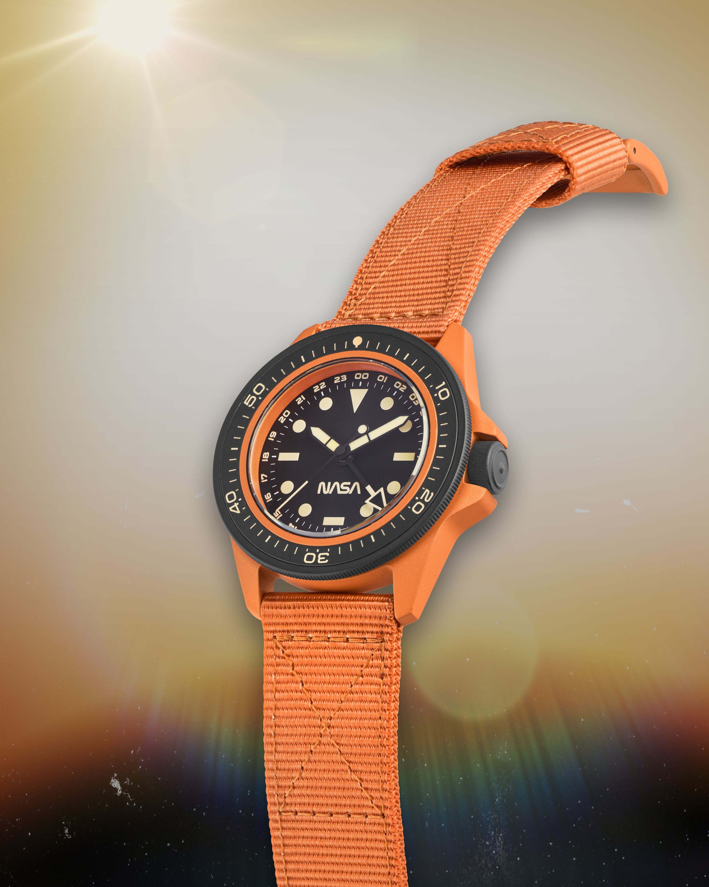 an orange watch with a black dial floating in space