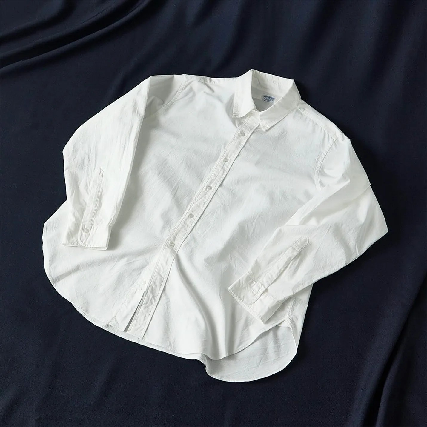 a white oxford shirt laying on a navy blue sheet
