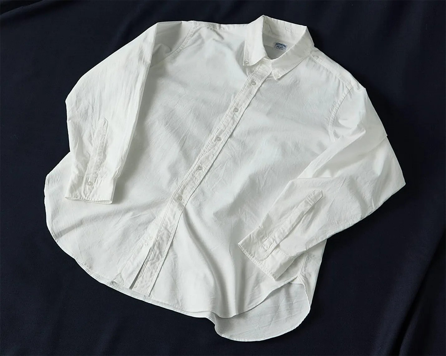 a white oxford shirt laying on a blue sheet