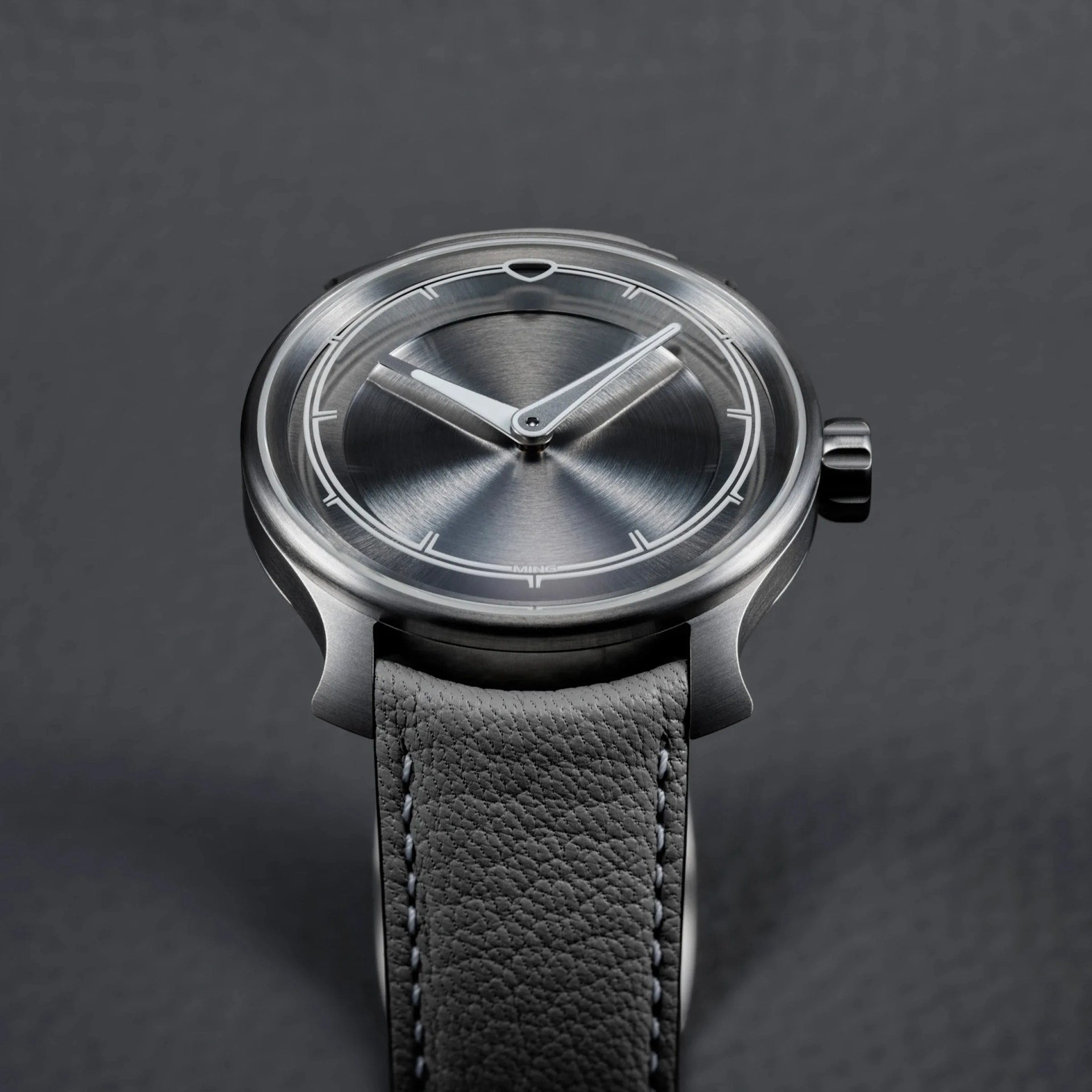 a titanium watch with a gray leather strap