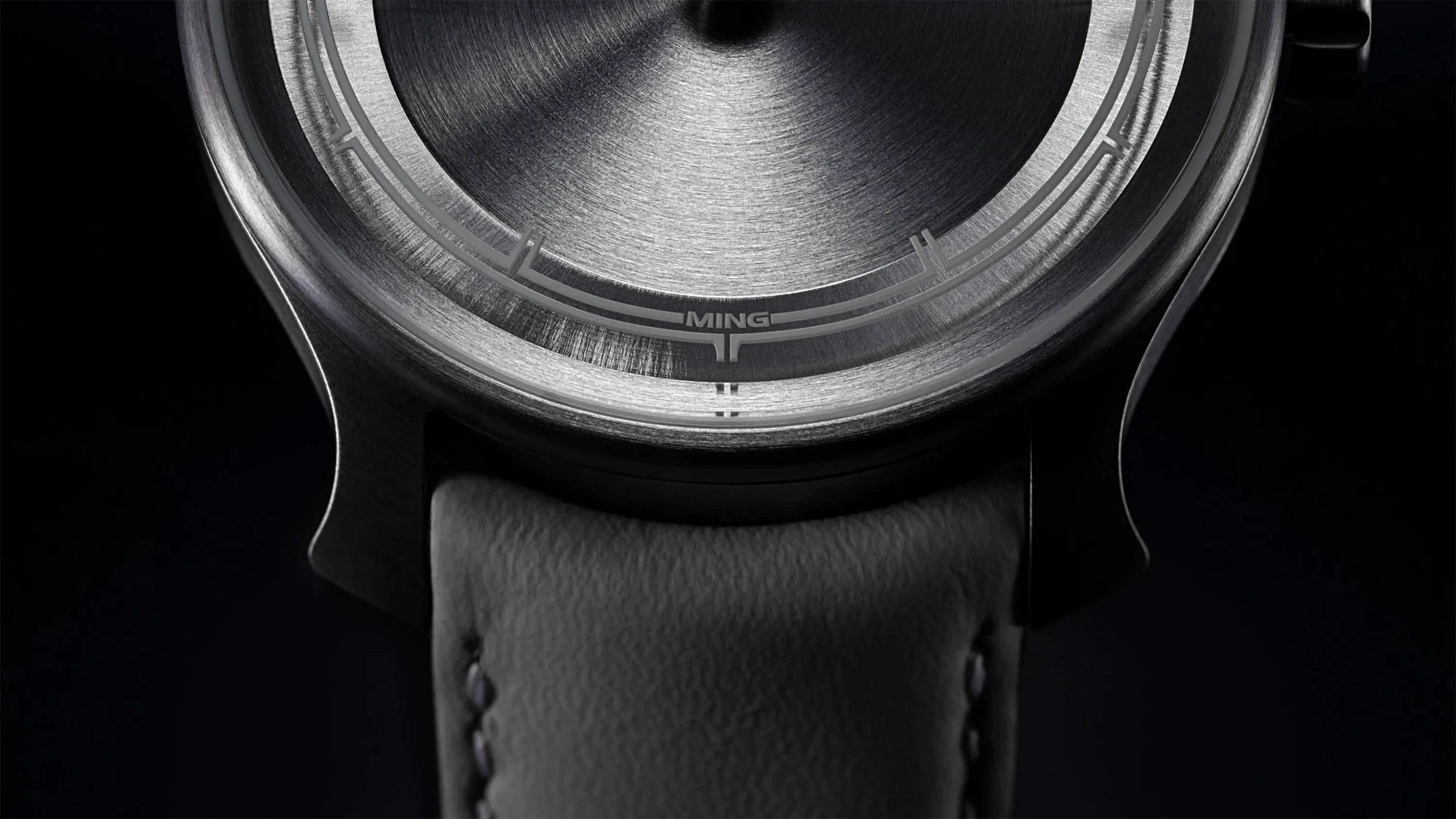 a titanium watch with a gray leather strap