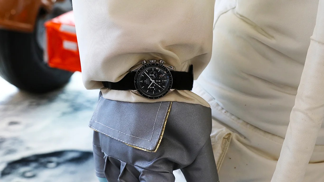an omega speedmaster watch on the wrist of an astronaut suit