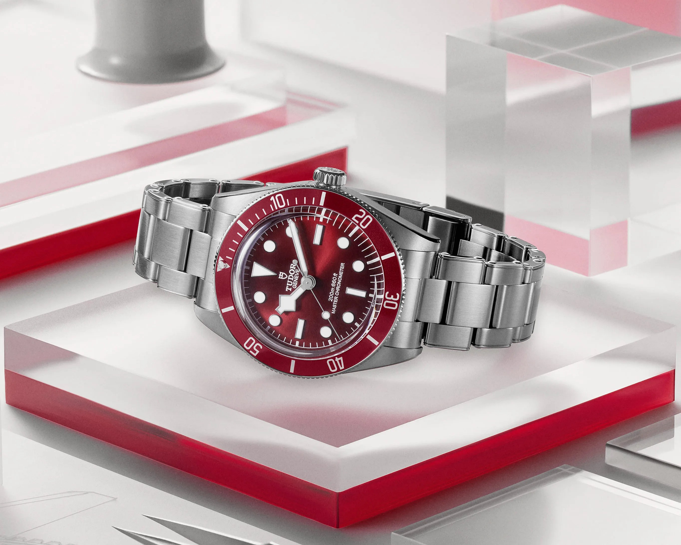 a steel dive watch sitting on a clear pedistal