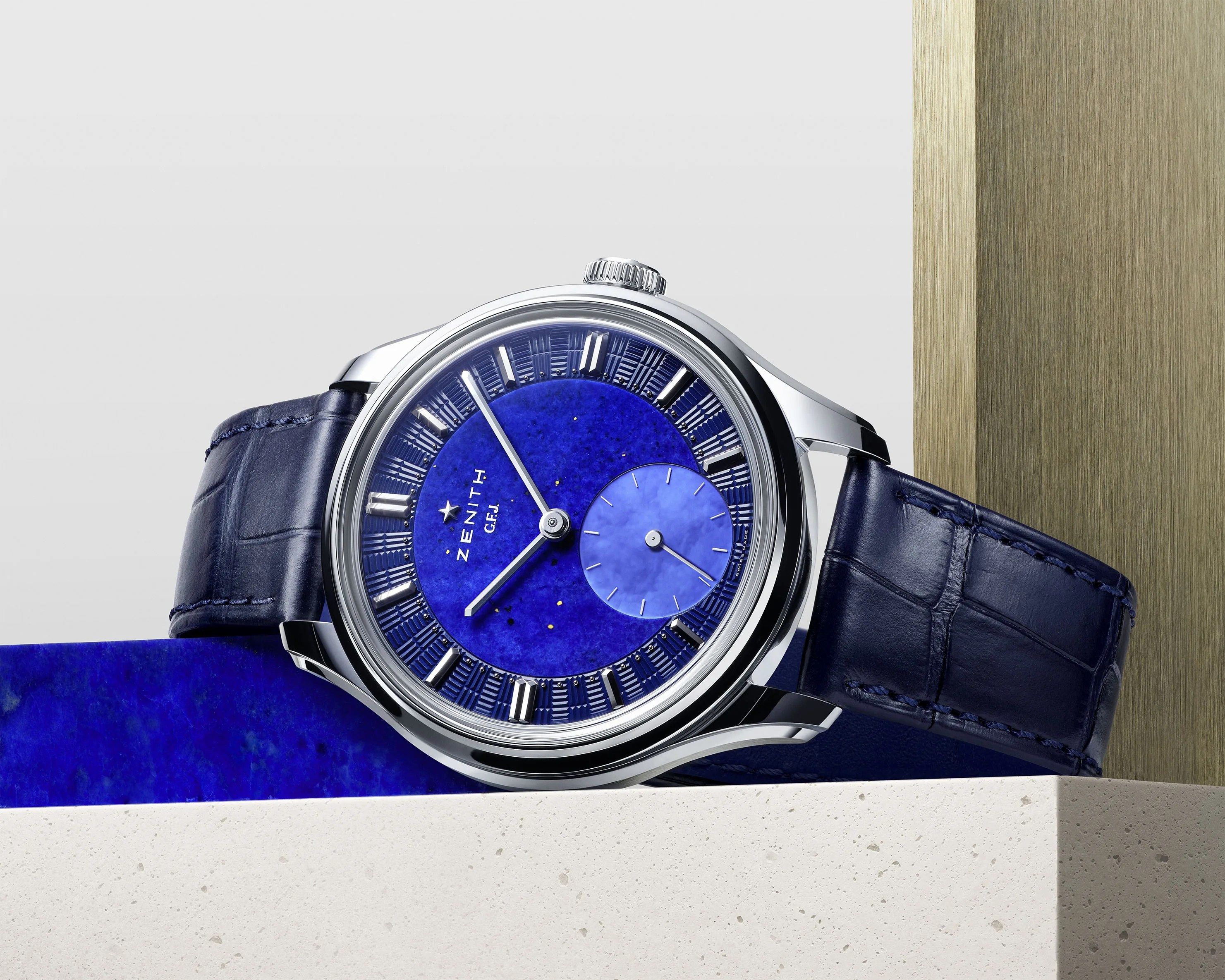 a Zenith watch with a blue dial laying on a table