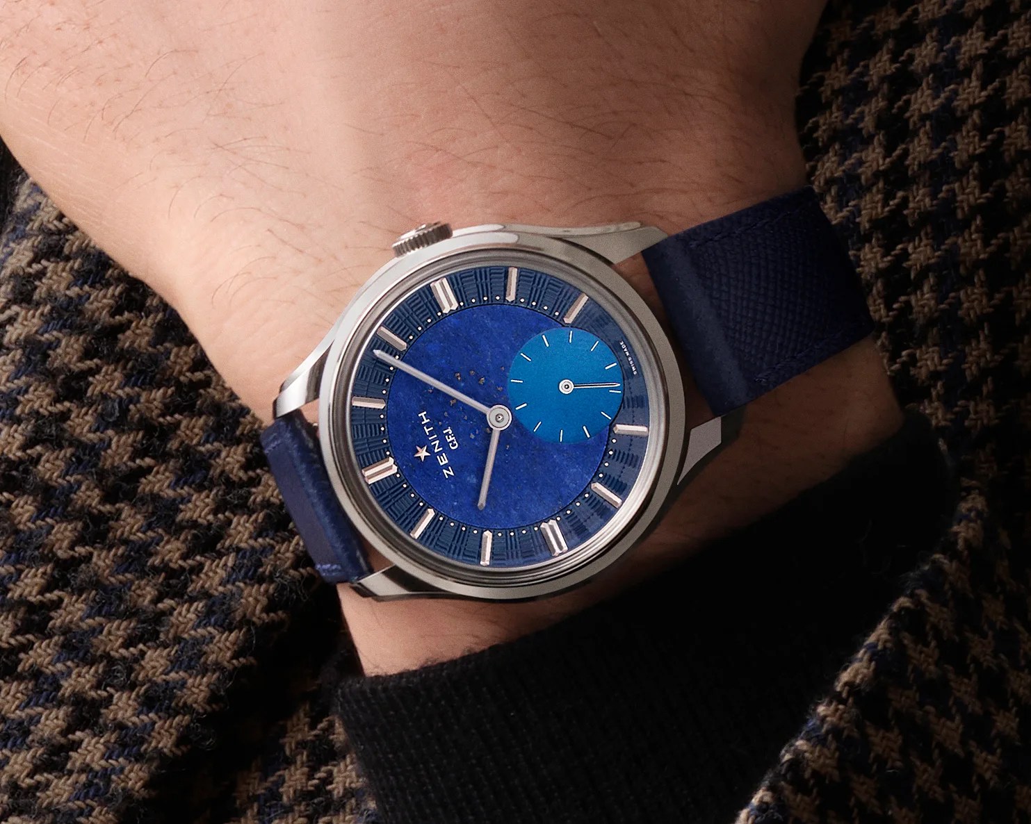 a Zenith watch with a blue dial on a man's wrist
