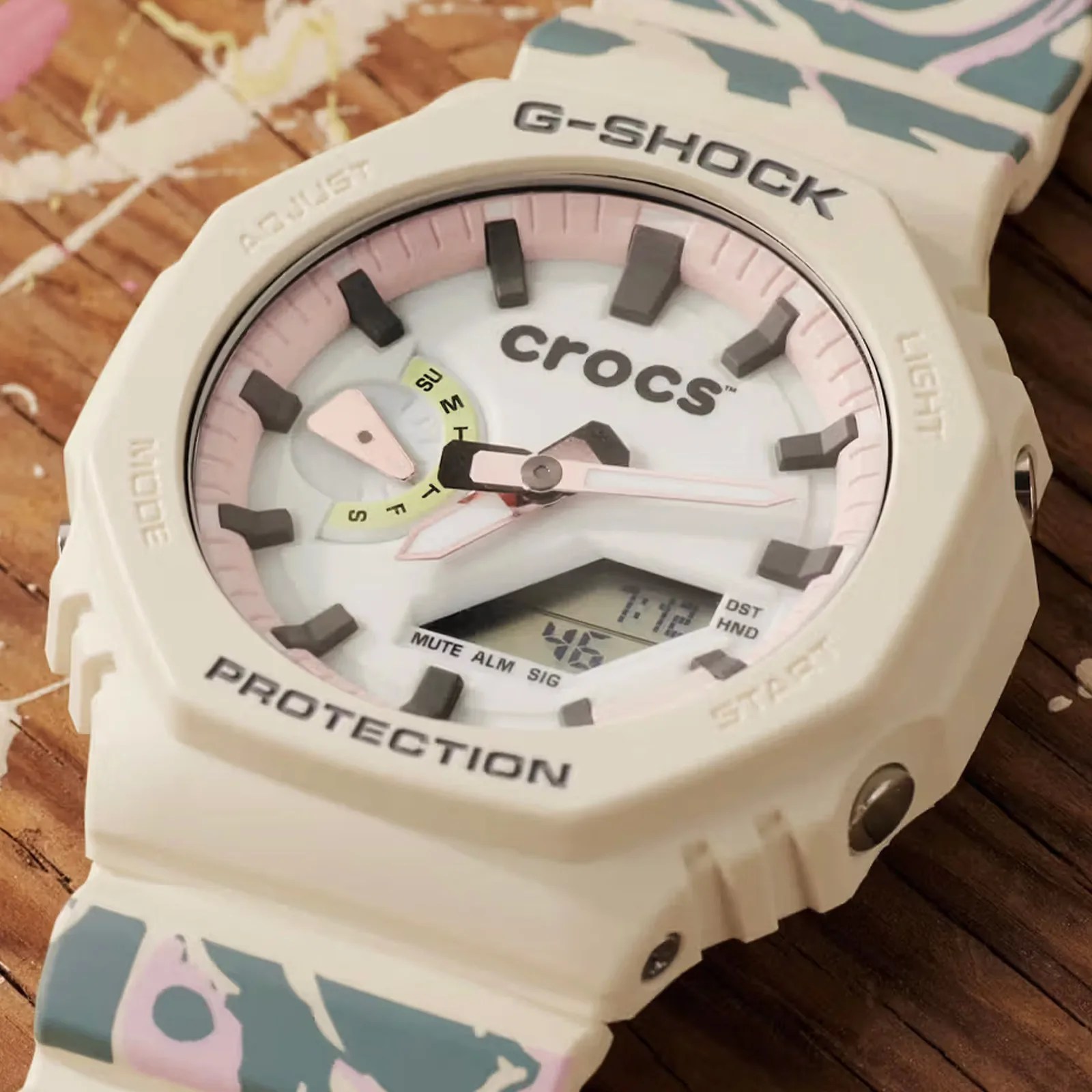 A close-up of the face of the G-Shock x Crocs Echo Wave watch highlighting its combination of cream and light pink colors. 