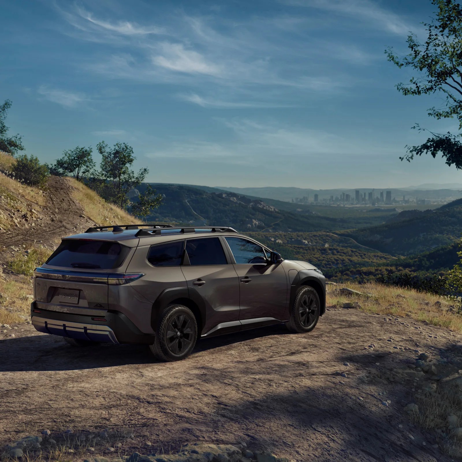 An image of the Toyota bZ Woodland EV parked on a ridge facing a city in the far distance