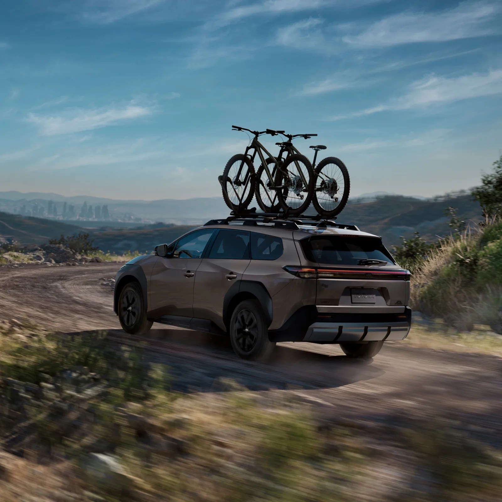 An image of the Toyota bZ Woodland EV driving away down a direct road fast with bikes on the roof