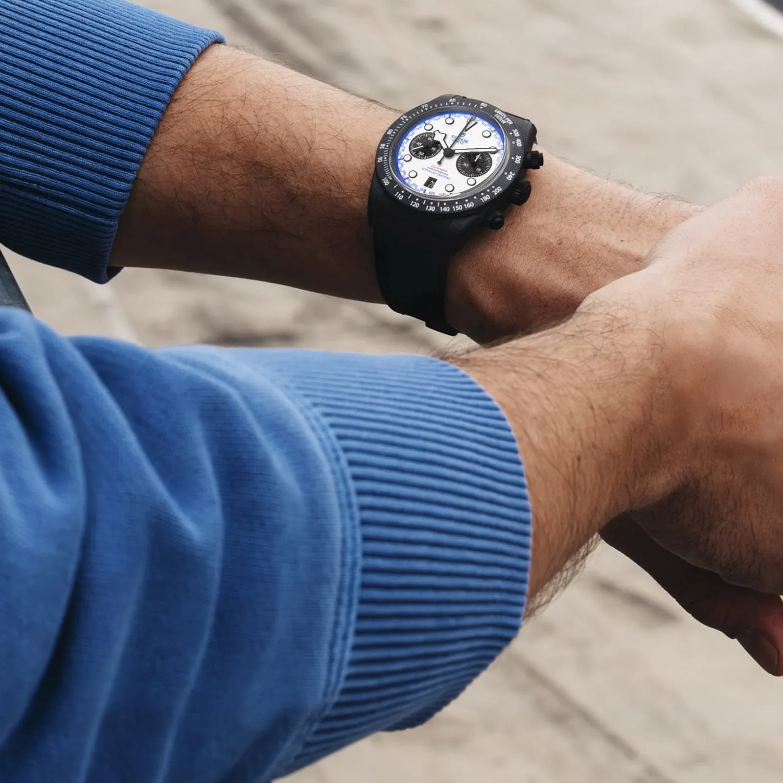 Tudor Black Bay Chrono "Carbon 25" watch being worn on a man's wrist wearing a blue sweater
