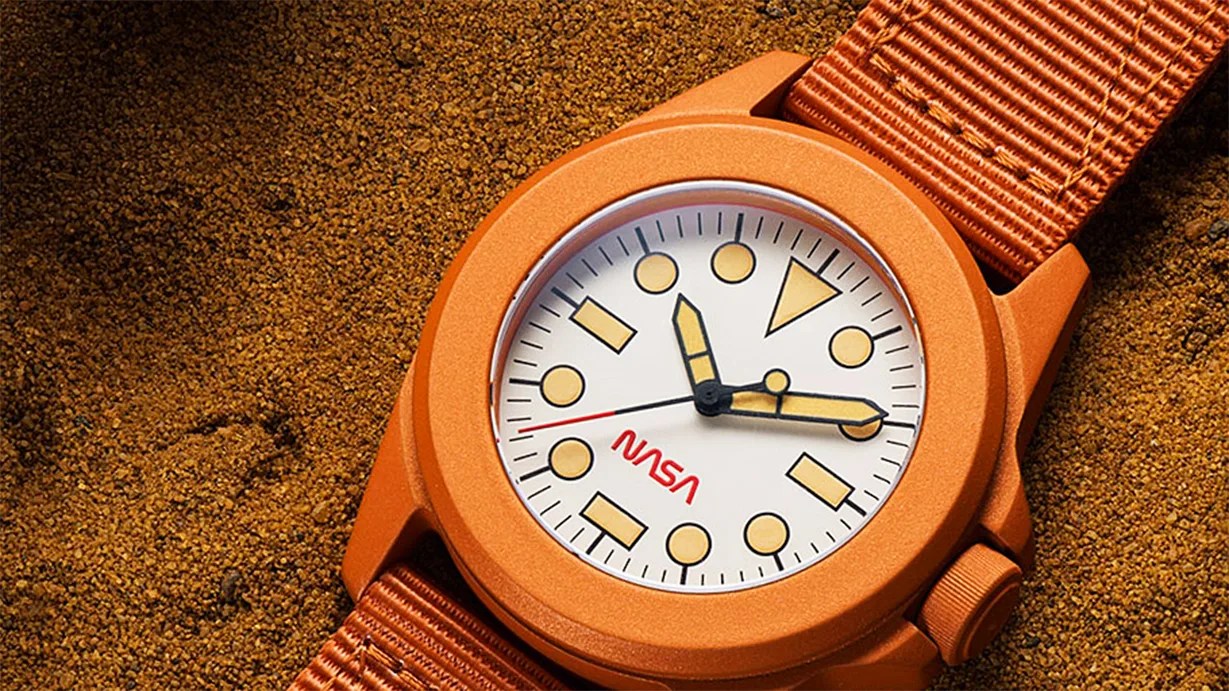 an orange watch in sand