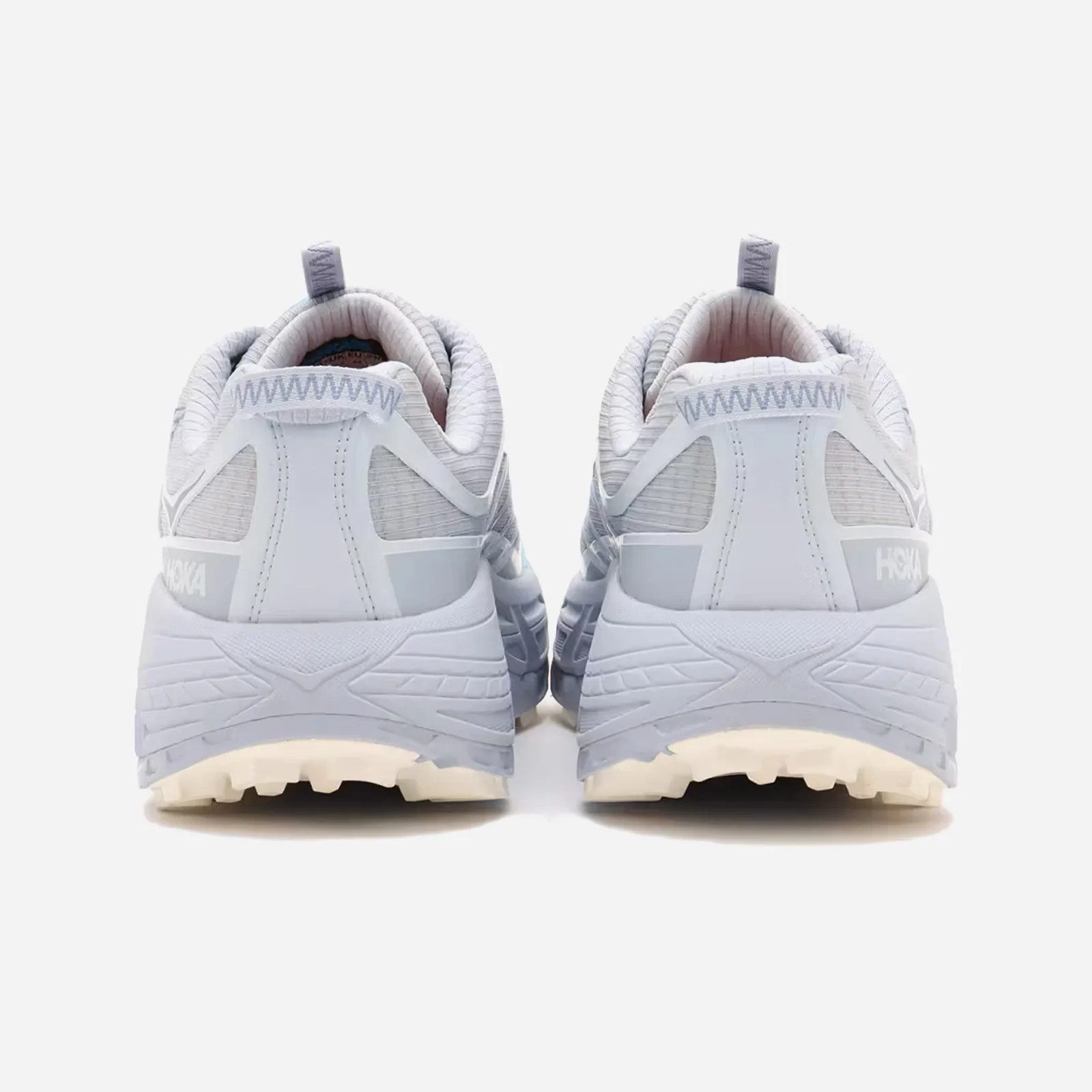 A pair of Hoka Mafate Three2 Grid JP in "Gull / Pale Dusk" shown from above placed on a wooden bench. 
