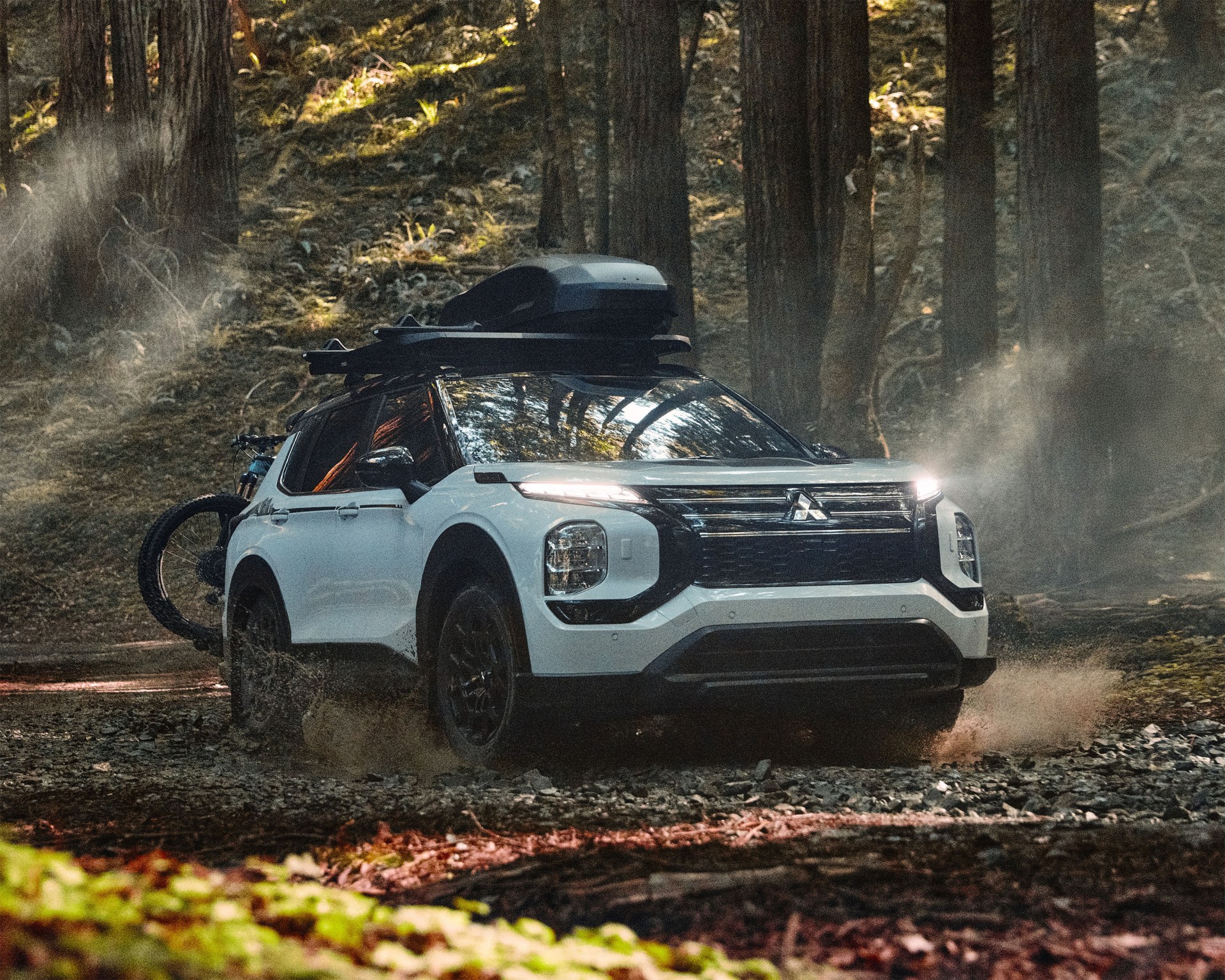 a photo of a white mitsubishi outlander in a forest clearing