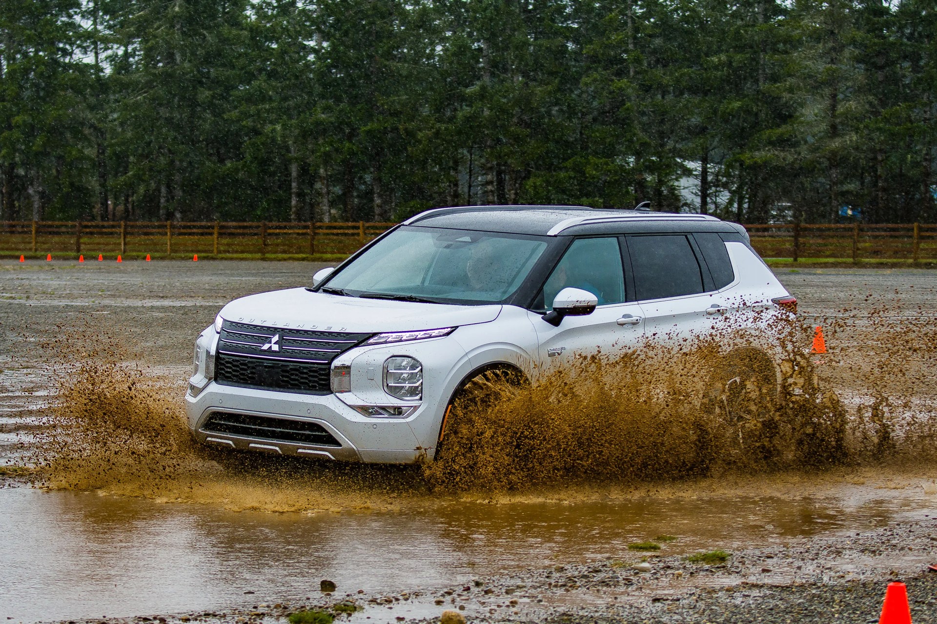 a photo of a white mitsubishi outlander suv driving through mud