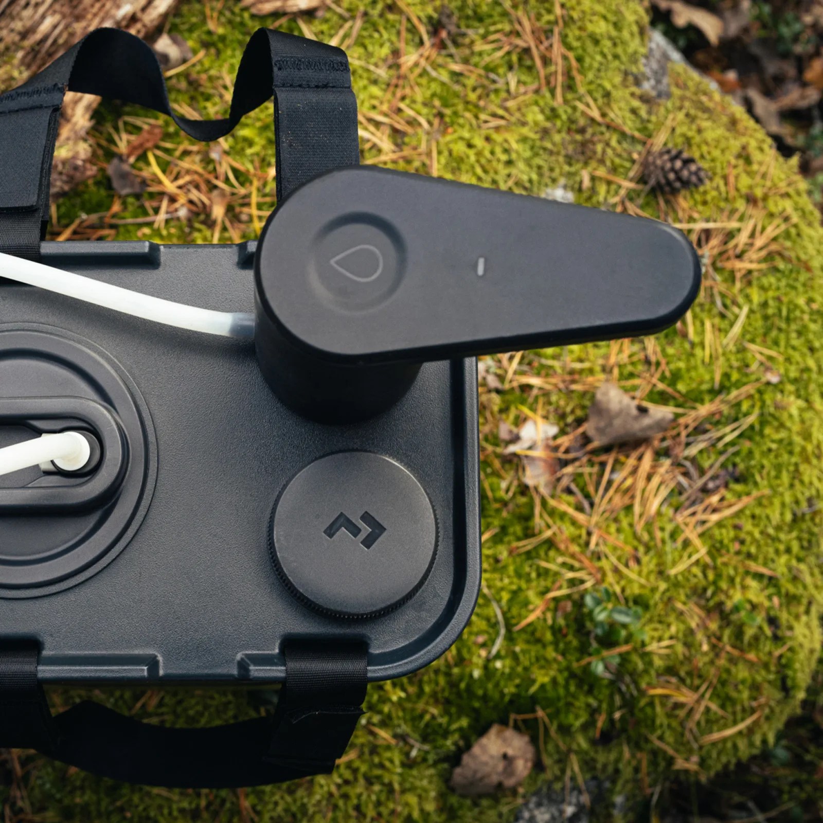 Dometic GO Hydration Water Faucet shown from above sitting on top of a Dometic water jug resting on mossy ground