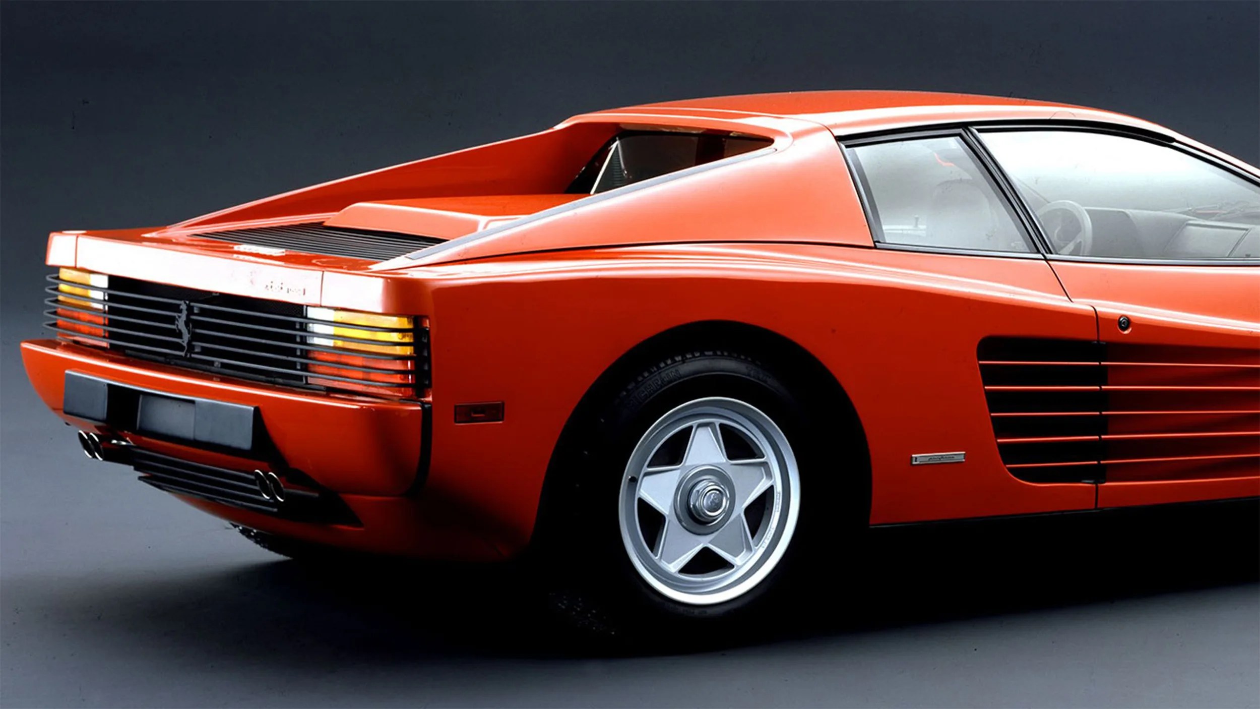 photo of rear 3/4 of ferrari testarossa sports car studio backdrop