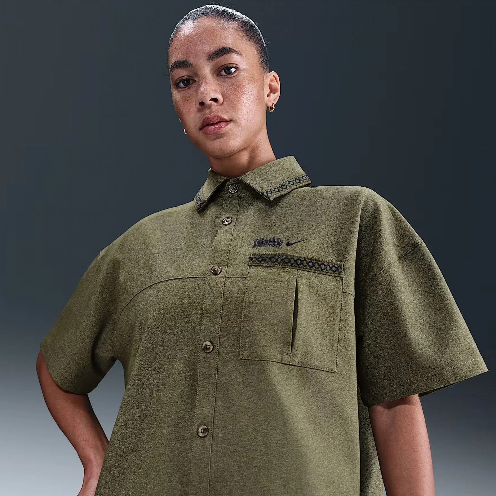 A female model shown wearing the Nike Naomi Osaka Oversized Short-Sleeve Top in Olive