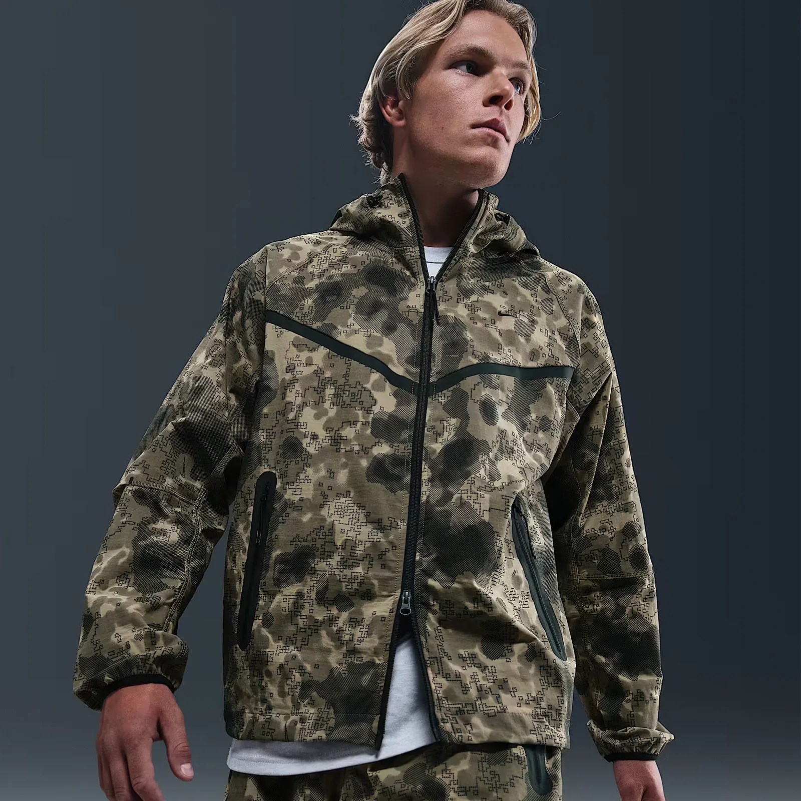 A male model wears a camo patterned Dri-Fit Windrunner jacket