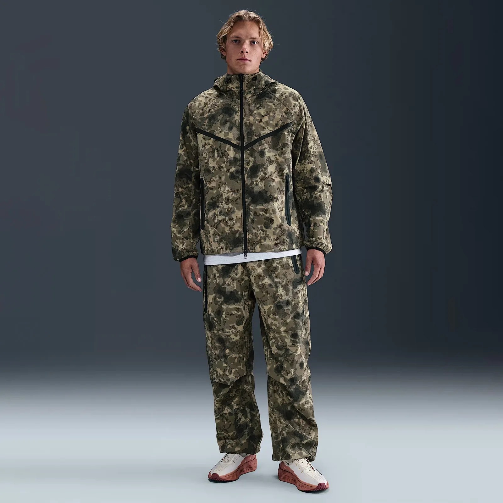 A male model wearing a full Nike warm up suit in digital camo
