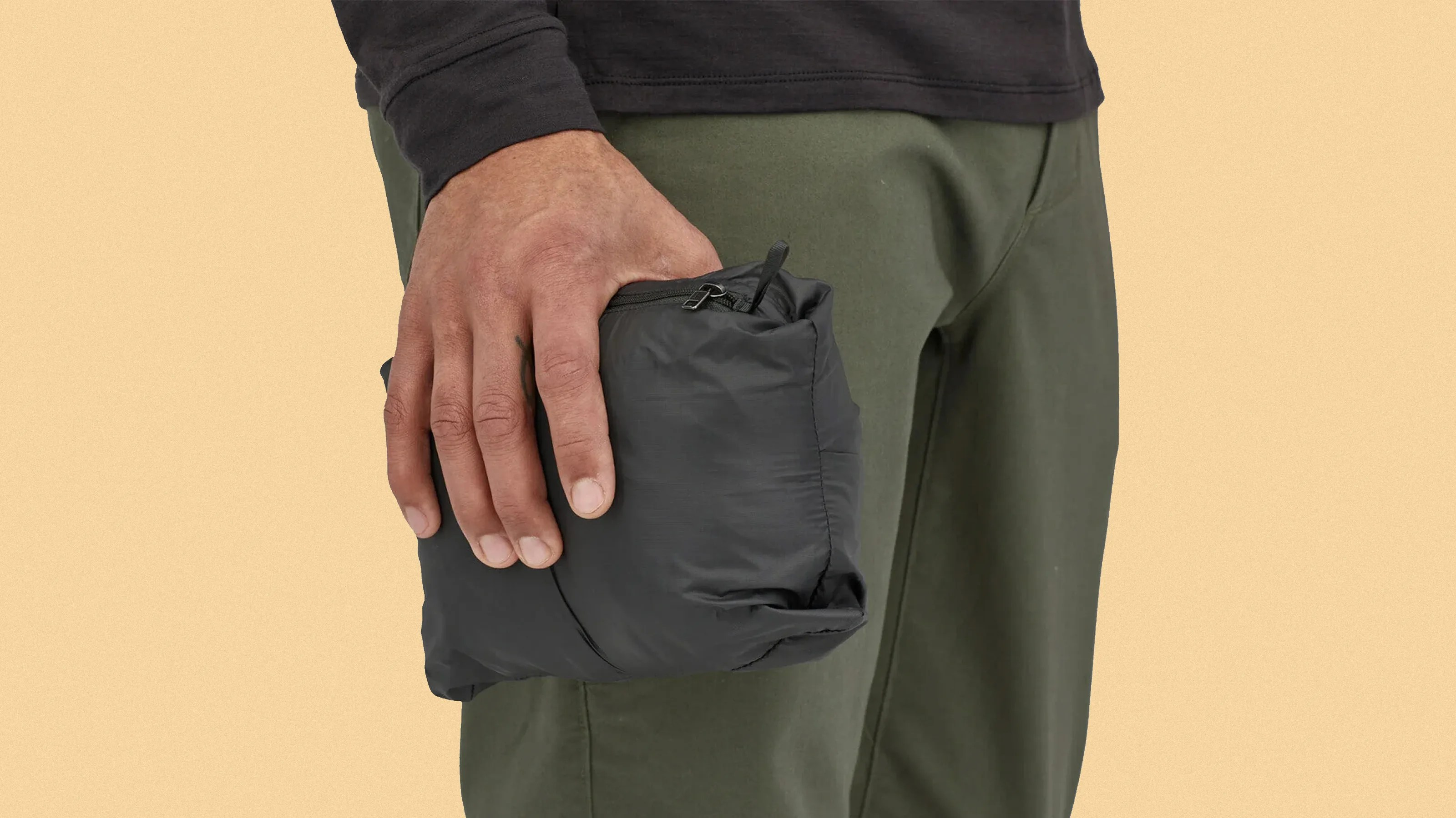 Patagonia Nano Puff jacket is black in its pouch being held in a man's hand