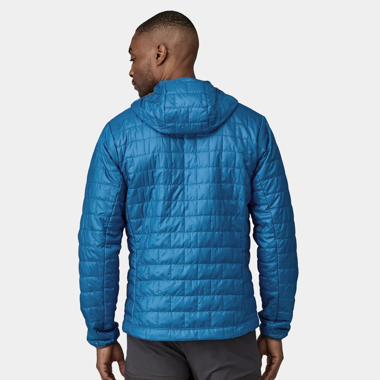 A male model shown from behind with his head turned to the left wearing a bright blue Patagonia Nano Puff hooded jacket