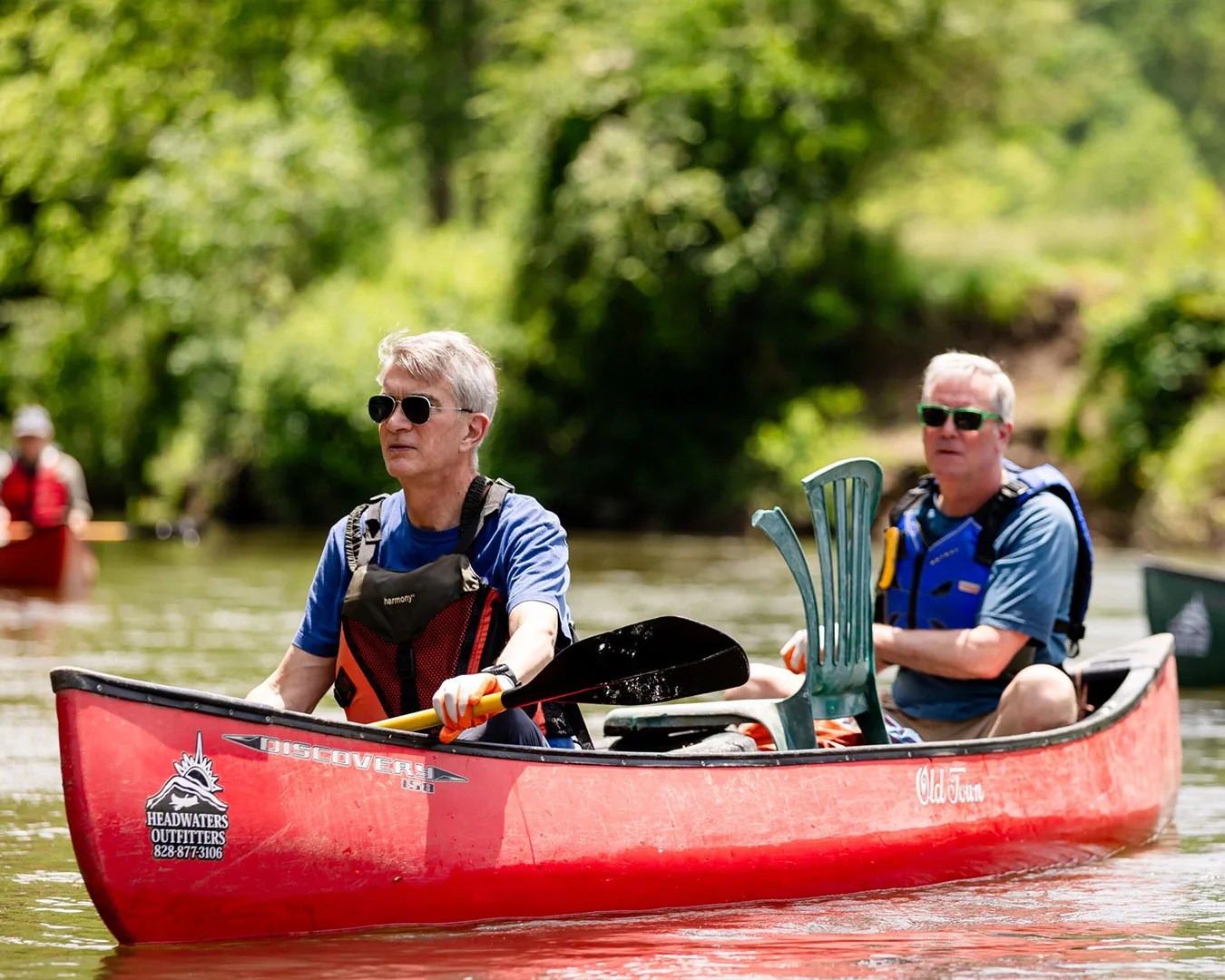 two older men paddling in red kayak
