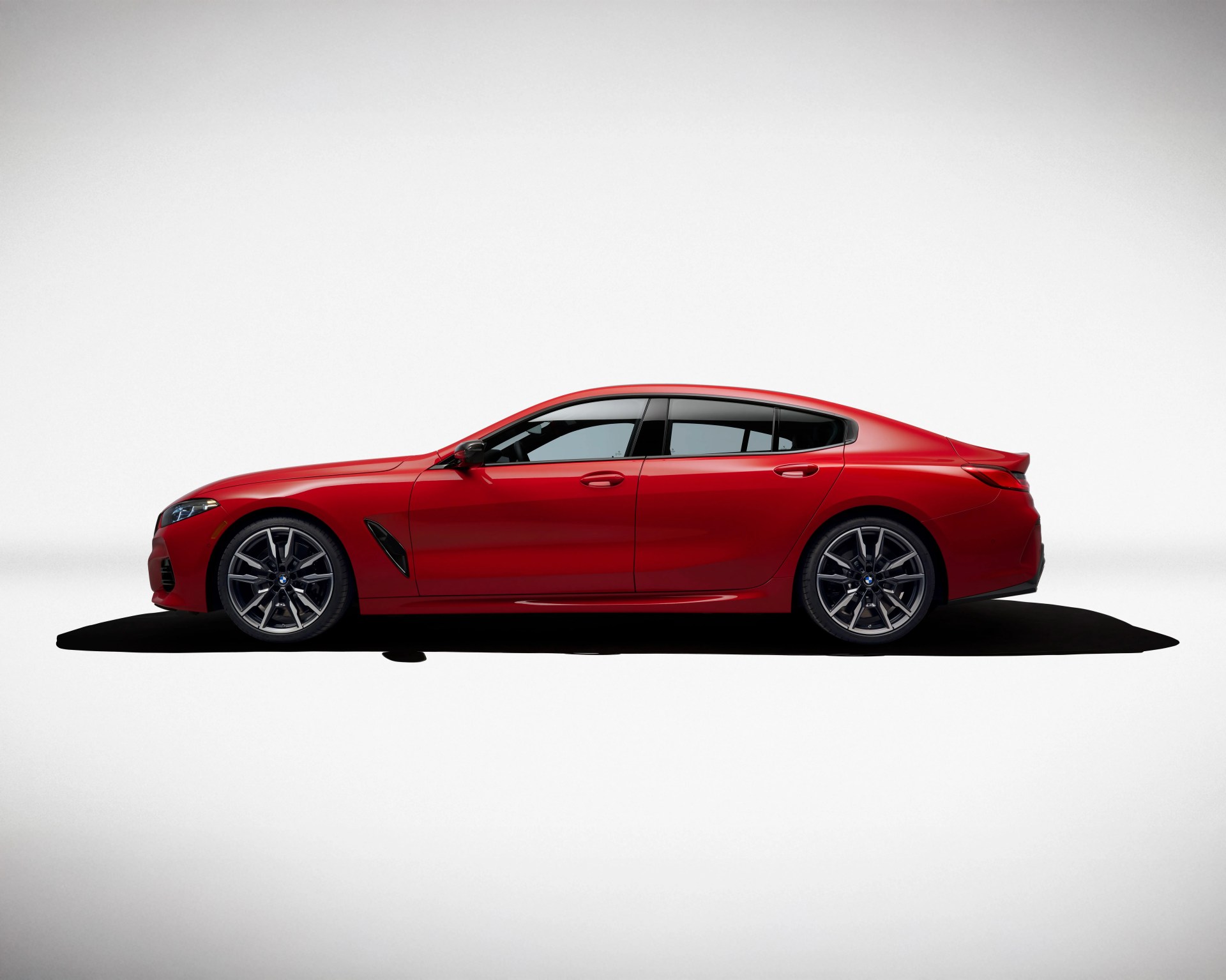 Red luxury sports sedan with sleek, aerodynamic design, black-tinted windows, and multi-spoke alloy wheels.