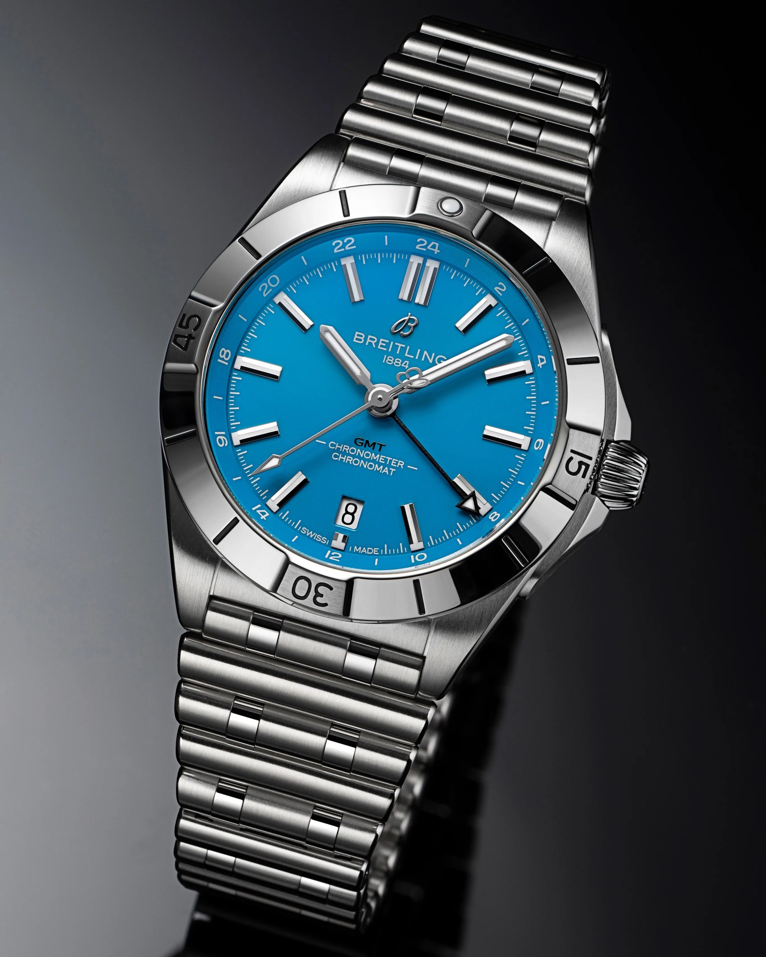 Stainless steel Breitling Chronomat GMT watch with a bright blue dial, silver hour markers, and hands. The watch features a date window at 6 o'clock, a 24-hour GMT hand with an arrow tip, and a polished bezel with engraved numerals. The bracelet is a matching stainless steel link design.