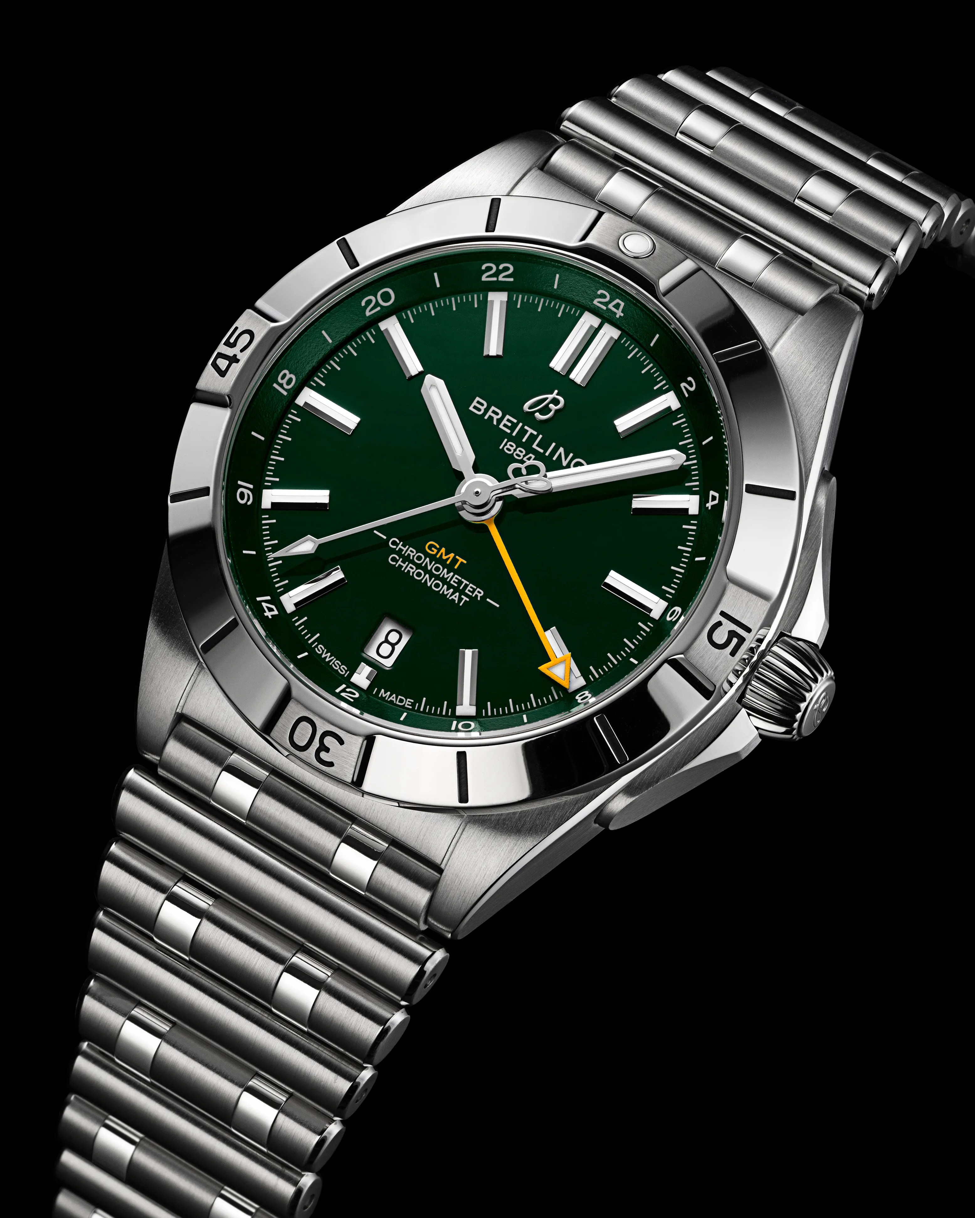Stainless steel Breitling Chronomat GMT watch with a green dial, silver hour markers, and hands. The watch features a date window at 6 o'clock, a yellow GMT hand with an arrow tip, and a rotating bezel with black markings. The bracelet is a polished and brushed stainless steel link design.
