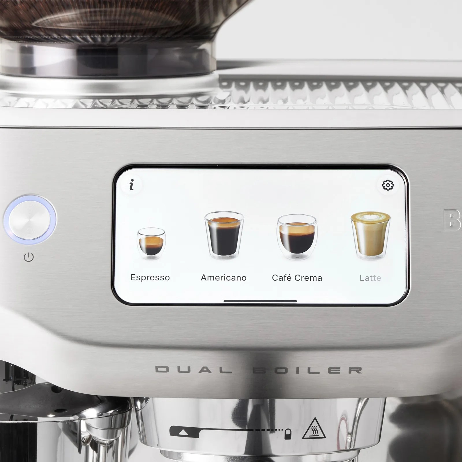 Touchscreen display on a stainless steel coffee machine showing four coffee options: Espresso, Americano, Café Crema, and Latte, with icons of corresponding coffee cups. The machine has a round power button with a blue light on the left and the text "DUAL BOILER" below the screen.