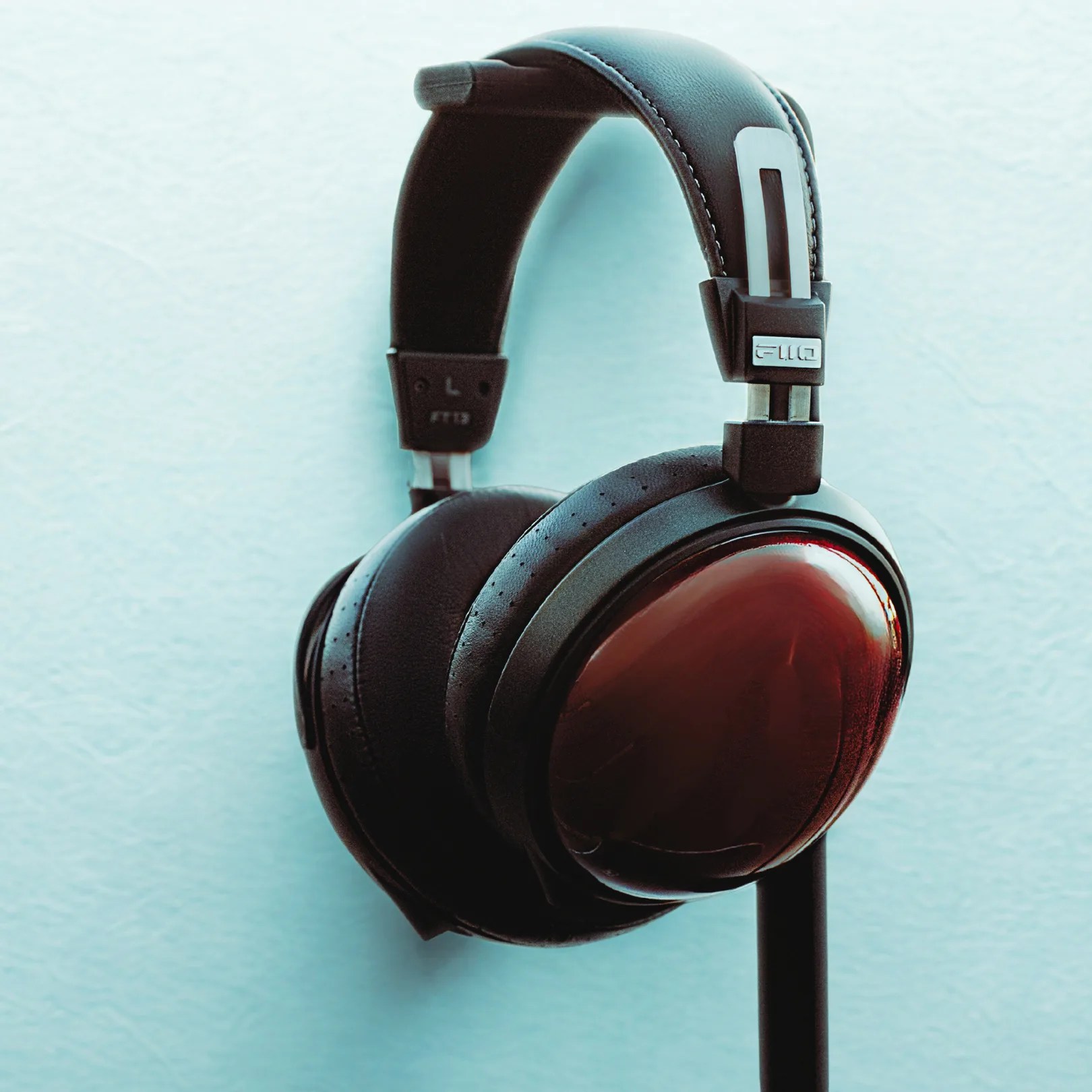 Over-ear headphones with black padded ear cups and headband, featuring glossy dark brown wooden outer ear cup covers and metal accents on the headband.